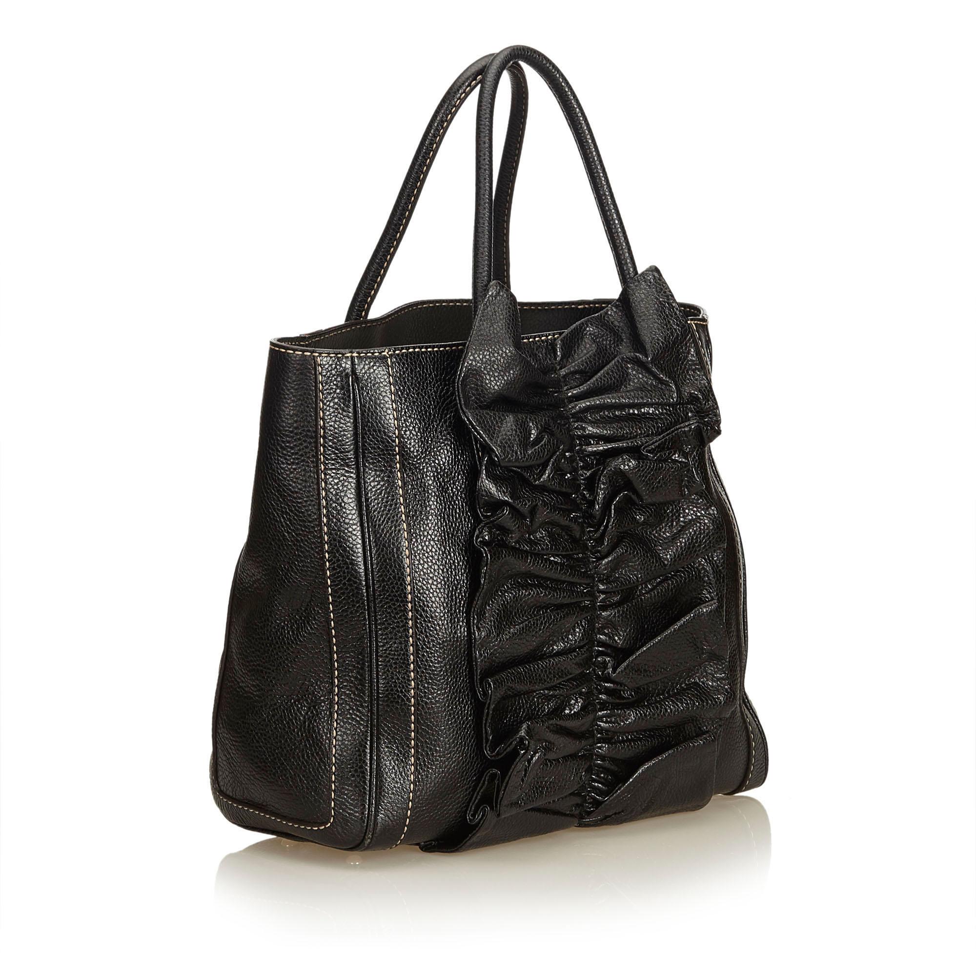 This tote bag features a leather body with ruffled leather detail, rolled leather handles, open top, and interior zip pocket. It carries as AB condition rating.

Inclusions: 
Dust Bag
Authenticity Card

Dimensions:
Length: 29.50 cm
Width: 34.50