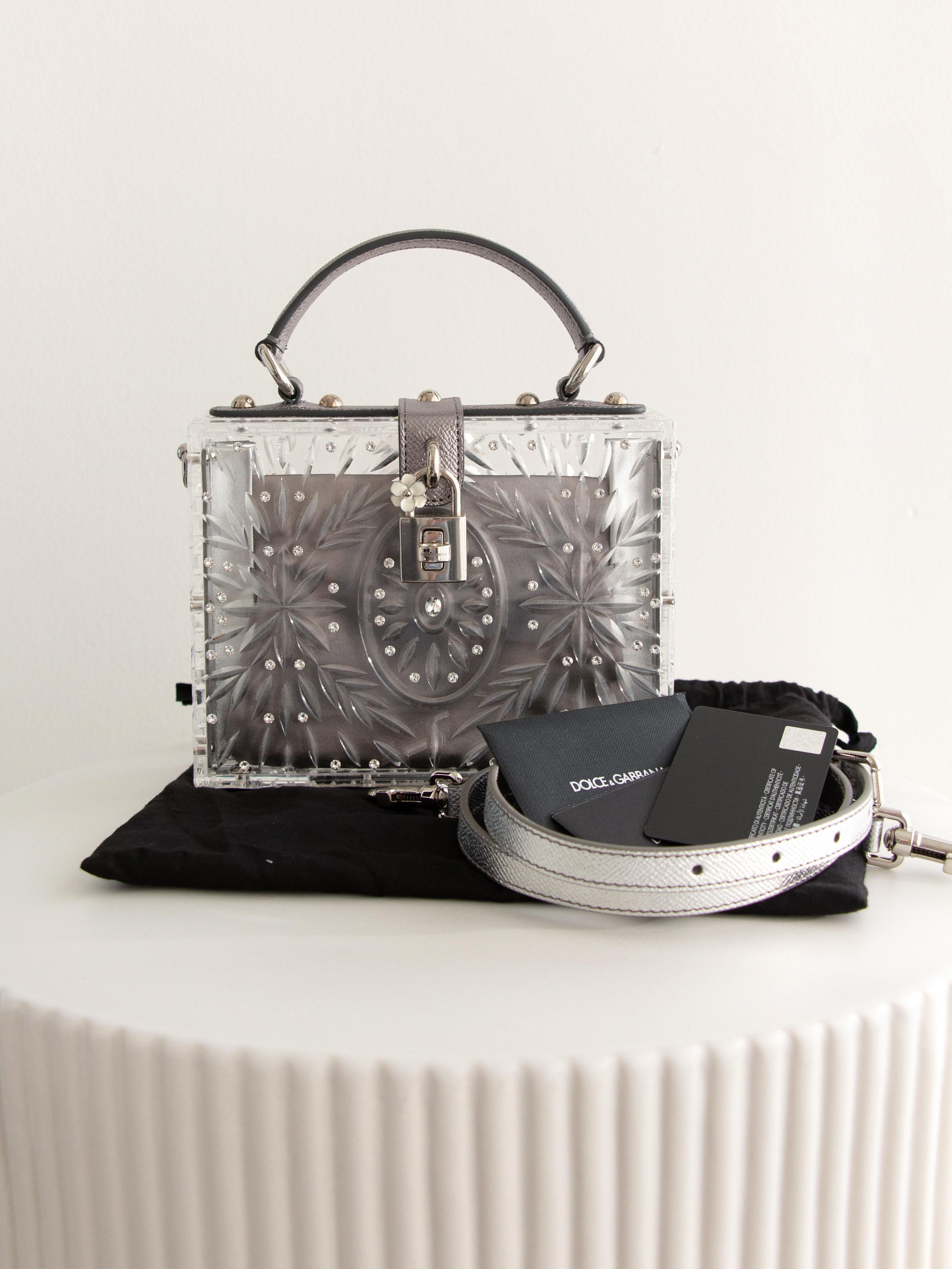 The Dolce & Gabbana Cinderella Dolce Box is a stunning example of the brand's dedication to luxury and artistry. Crafted from high-quality clear plexiglass, the bag features intricate floral and geometric patterns adorned with shimmering embedded