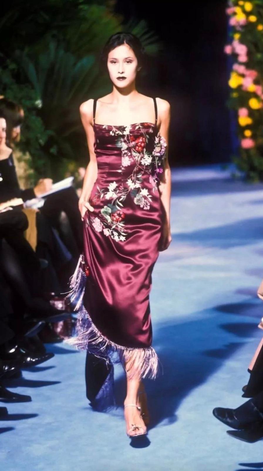 This striking Dolce & Gabbana dress from the Fall/Winter 1998 collection is a rare archival piece that captures the romantic sensuality of the era. Crafted from rich burgundy silk, the dress features exquisite hand-painted floral motifs in vibrant