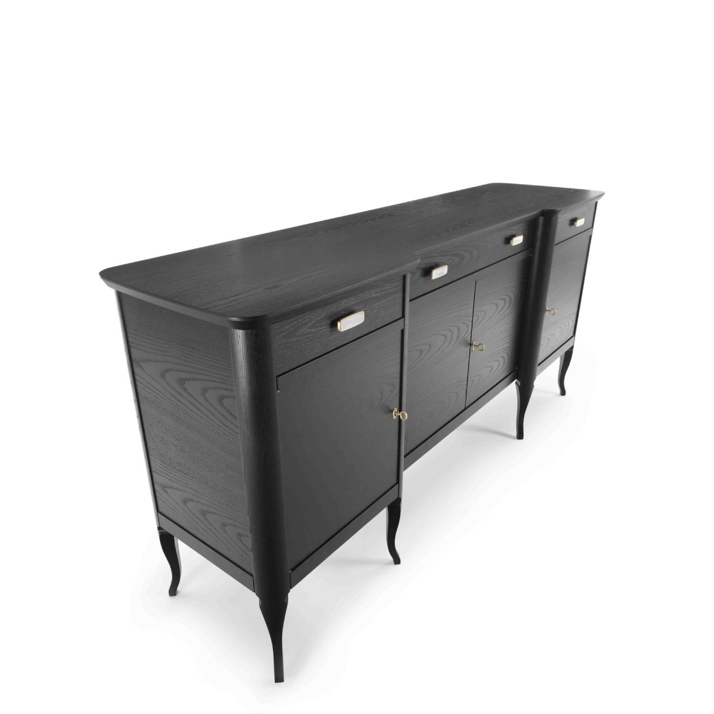 Revisiting a midcentury silhouette with modern sensibility, this refined sideboard is characterized by a sleek design that exudes timeless elegance and formal balance. A dark, ebonized finish adorns the ash-veneered frame that has four doors