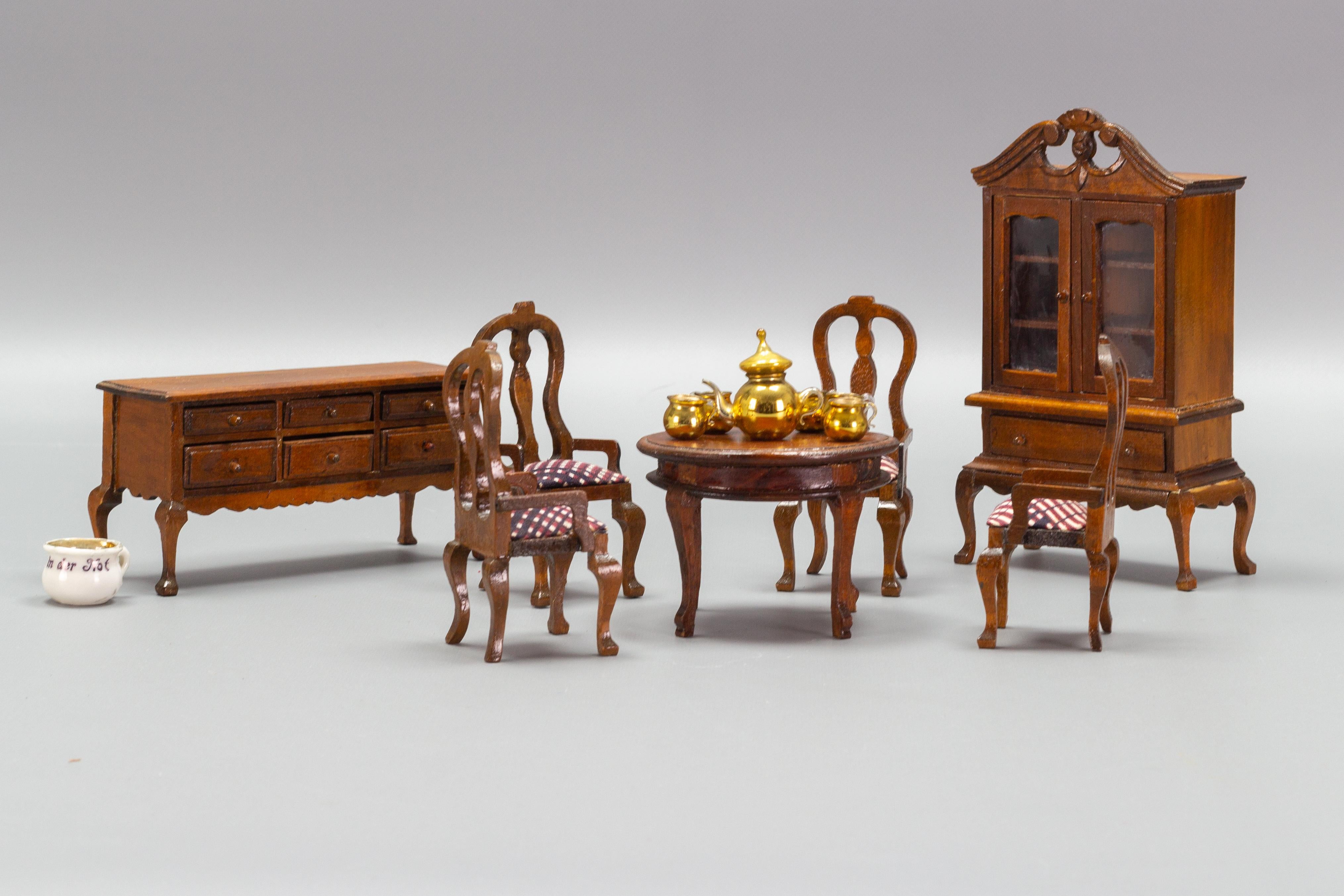 Adorable miniature doll furniture set, made of wood, Germany, 1970s.
This beautiful Chippendale-style dining room furniture set consists of a round table and four chairs, a chest of drawers, and a cupboard. 
Dimensions of the cupboard: height: 18 cm