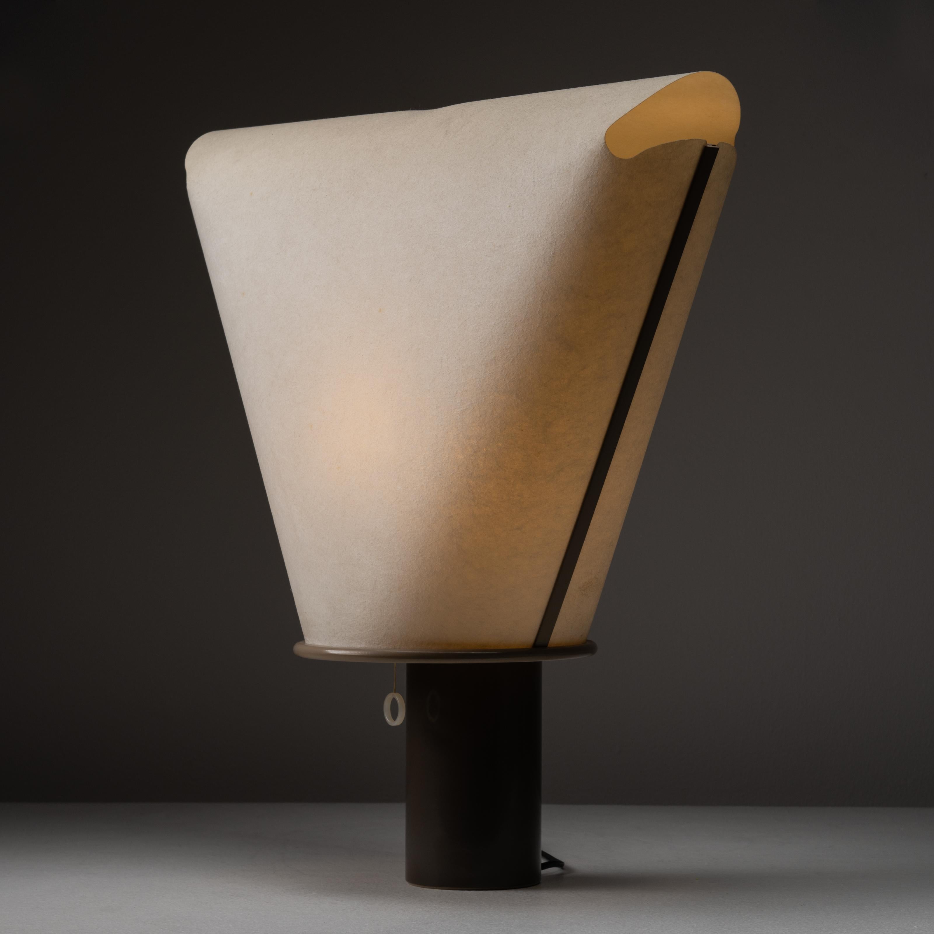 Dolly A 200 Desk Lamp by King & Miranda for Arteluce. Designed and manufactured in Italy, circa 1970s. Unique table lamp with lantern like waxed paper shade in the shape of a soft triangle, with a solid plastic cylindrical base. Plastic ring pull