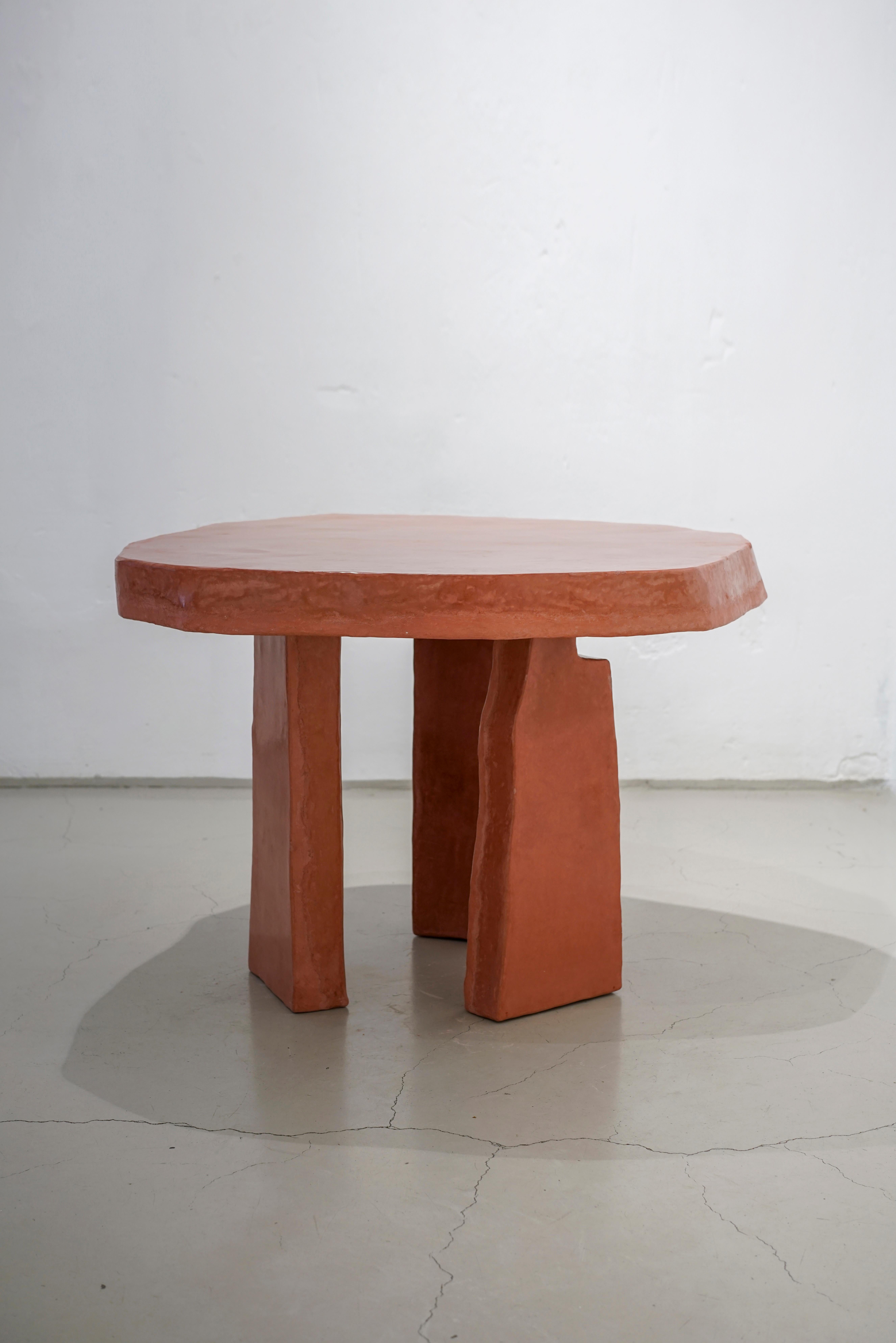 The monolithic-looking table is surprising through its unusual and raw aesthetic.The off-round top plate rests on three legs that look like unhewn stone blocks, reminding us of the typical dolmen shape. Aerated concrete builds the core of the table