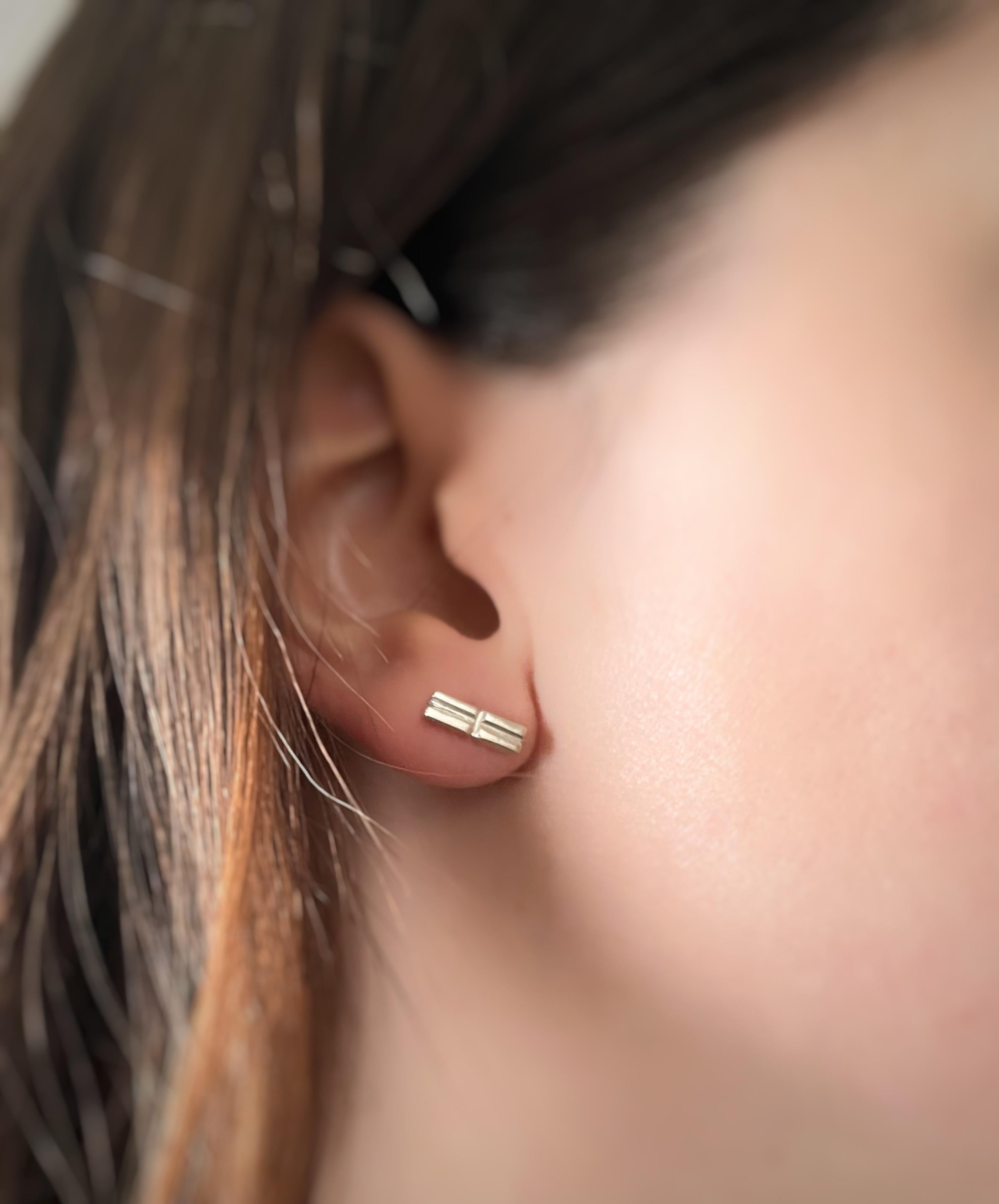 Minimal in size yet profound in meaning, these handcrafted 925 sterling silver earrings embody the delicate harmony of opposites. Designed in a modern rectangular form (3 mm x 10 mm), they feature subtle relief symbols inspired by “–” and “+,” a