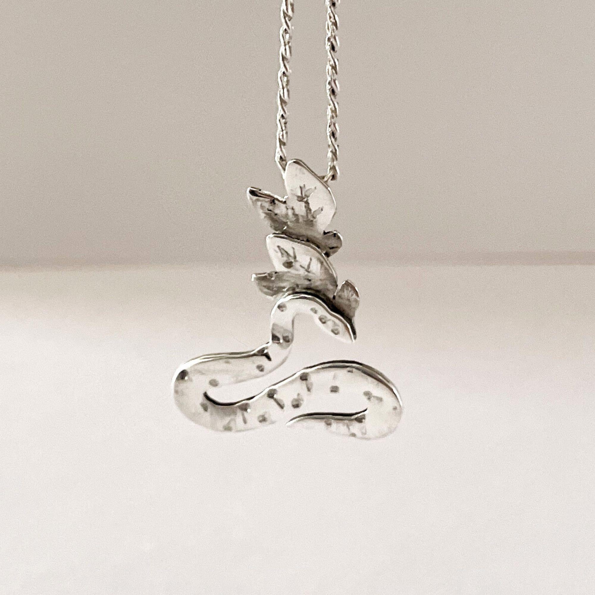 Questo ciondolo artigianale unico è realizzato in argento massiccio 925 e presenta un serpente arrotolato a forma di simbolo dell'infinito. Simboleggiando la rinascita, la protezione e l'eterno ciclo della vita, il motivo del serpente è arricchito