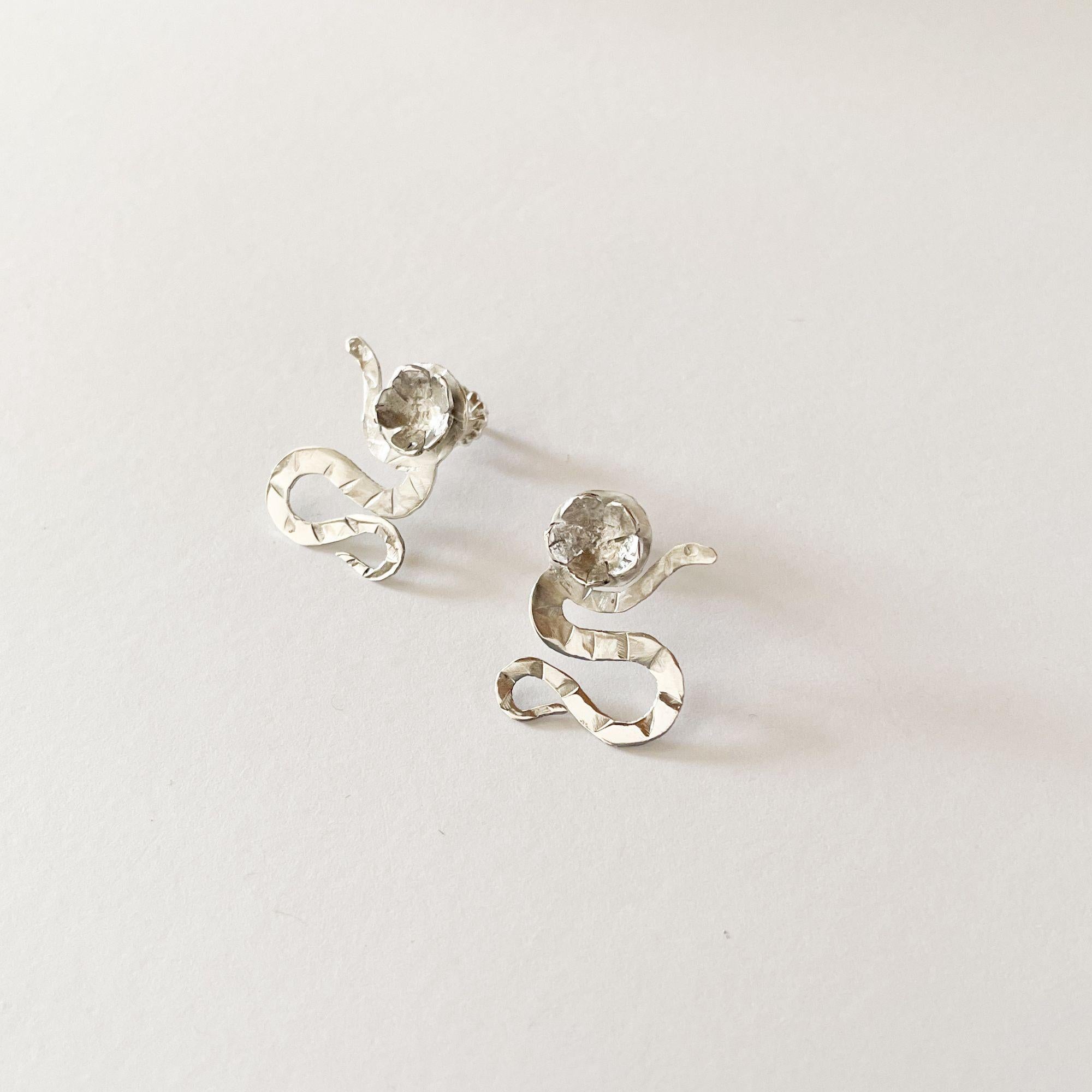 Celebra il potere della trasformazione con questi orecchini in argento sterling realizzati a mano da Dolores Ortega. Un serpente finemente dettagliato si avvolge intorno a un sakura (fiore di ciliegio) in fiore, creando una composizione poetica e