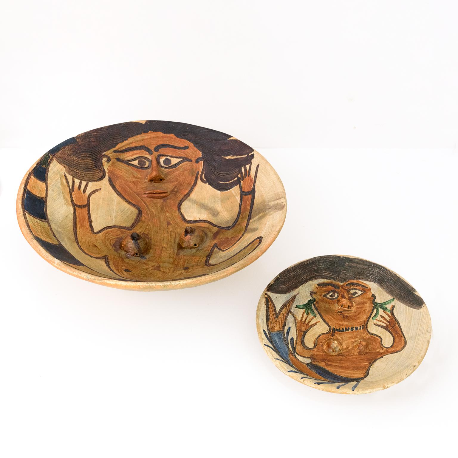 Two unique hand crafted clay bowls created by Dolores Porras. Polychrome glazed bas-relief each depicting mermaid with a nose and breast in high relief, the hands spread out next to the flowing hair, the tail bent next to the body, signed on the