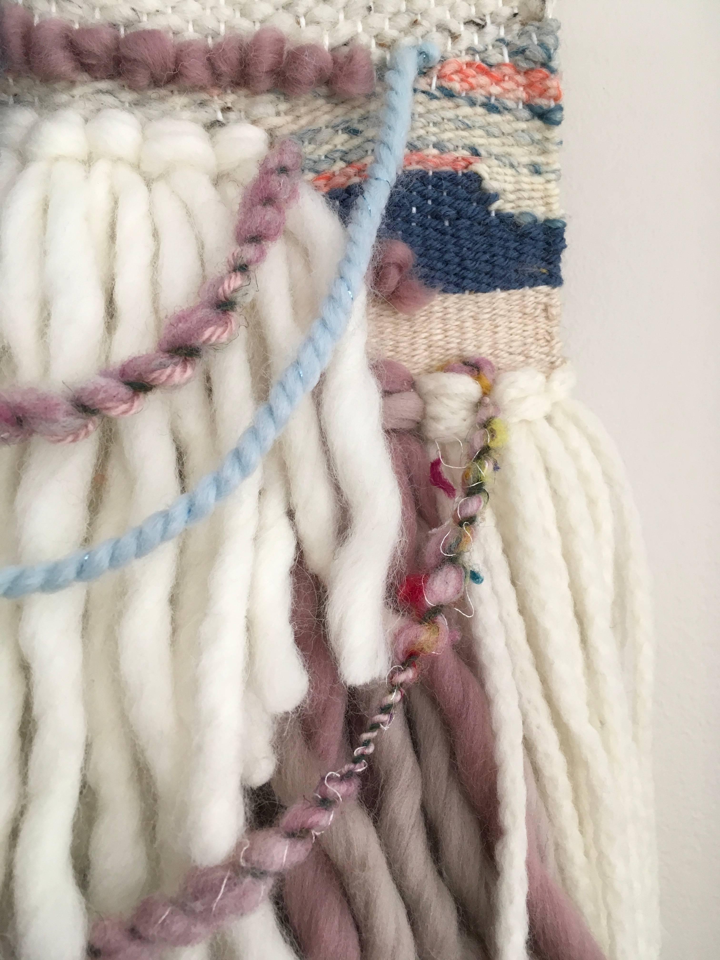 Ce tissage en fibre de Dolores Tema est réalisé avec du coton et de la laine mérinos et alpaga. Le tissage est encadré dans un cadre champagne chaud vieilli, et est tissé du haut vers le bas, avec des couleurs variées de rose sourd, beige, crème, et