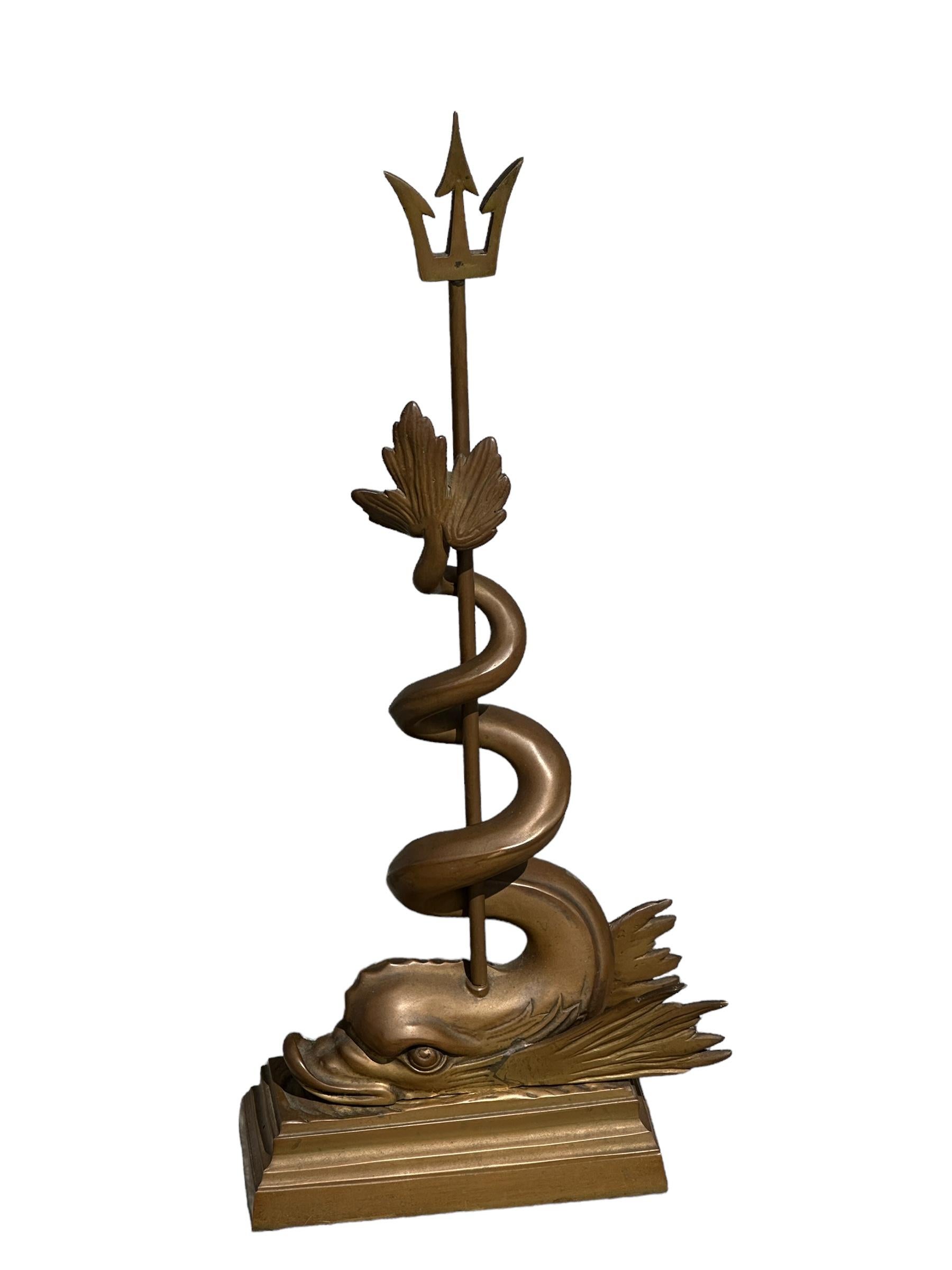 A beautiful and substantial Nautical, cast metal, antique doorstop with original patina finish. Depicting a mythological grotto dolphin style sea serpent coiled around Poseidon's trident which is then mounted on a multi tiered classical plinth. This