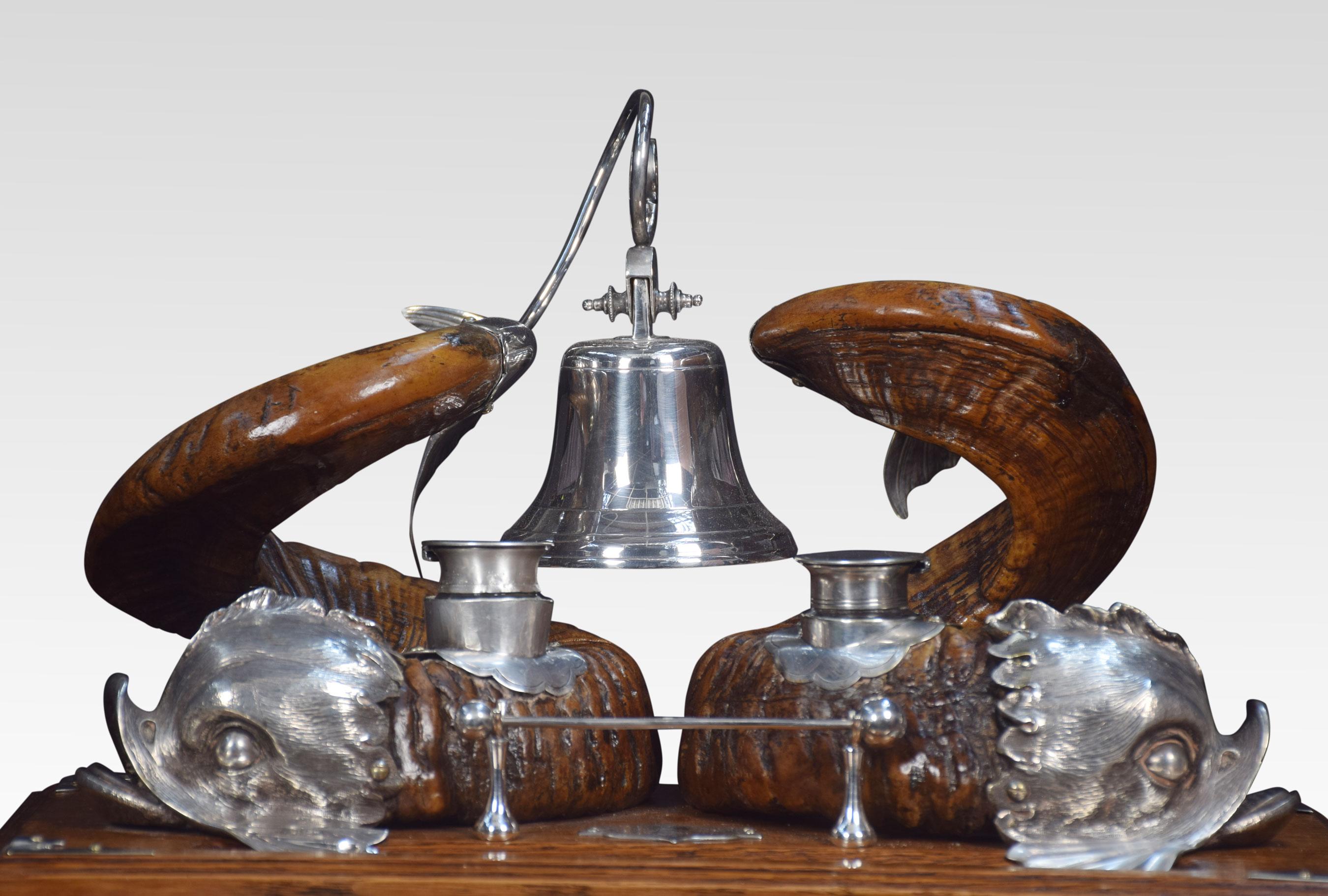 Ram Horn and silver plate dolphin inkwell, bearing a pair of ram’s horns, mounted with plated dolphin mounts, the tail suspending a bell, the beater for which is on mounts to the front near the pen well. All raised up on oak base with a central