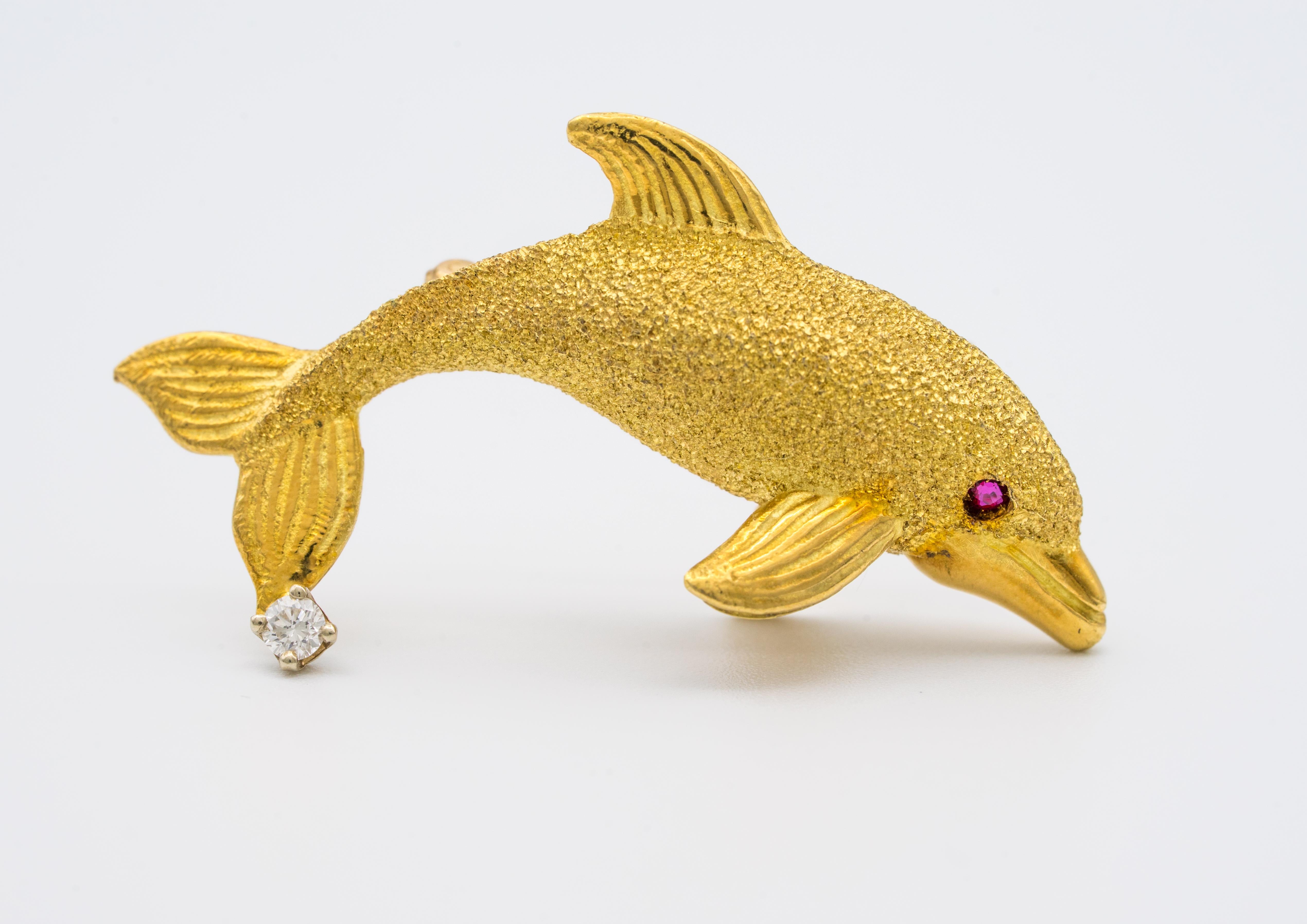 A vintage Dolphin pin in 18K yellow gold with a ruby eye and bezel set diamond.
Round brilliant diamond measures approximately 2.5mm and is G VS Color and clarity 

Dolphin measures: 1 3/8 x 5/8 inches.
Weighs 7.6 grams
We ship FedEx overnight to