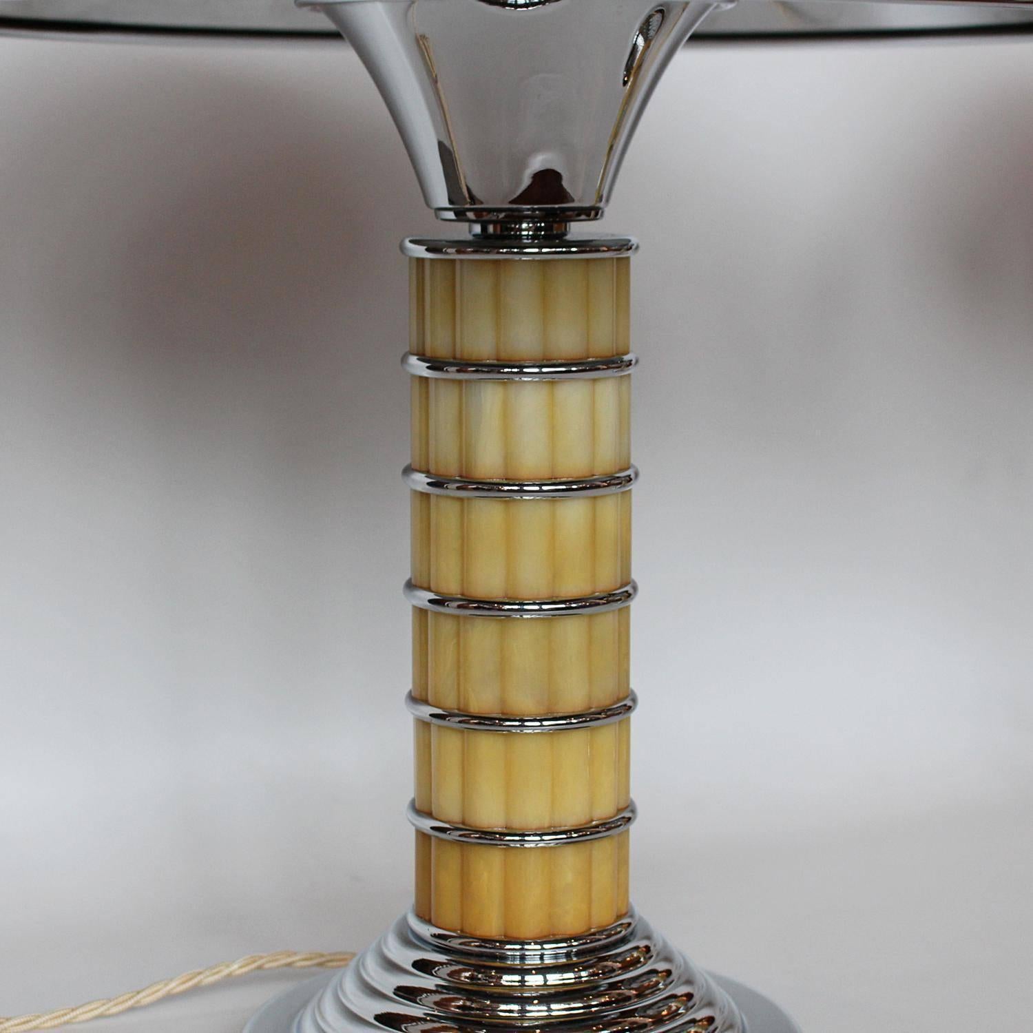 A pair of Art Deco table lamps with domed shades. Reeded, golden bakelite stems banded with chromed metal. Stepped metal bases. Bakelite finials to top.

Fully refurbished, re-wired and re-chromed, replacement shades.

Dimensions: H 45cm, W of