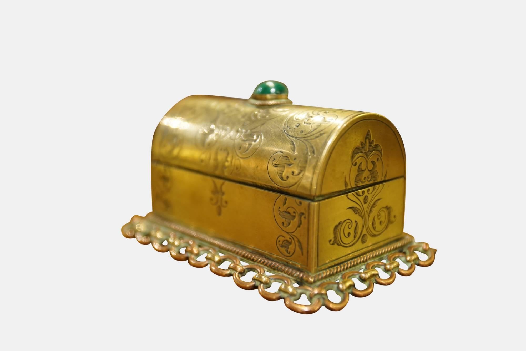 An unusual late 19th century dome lid engraved casket, the lid is set with a malachite cabochon.

Raised on chain link base

Likely a stamp or vesta box

Copperor brass alloys, circa 1880.