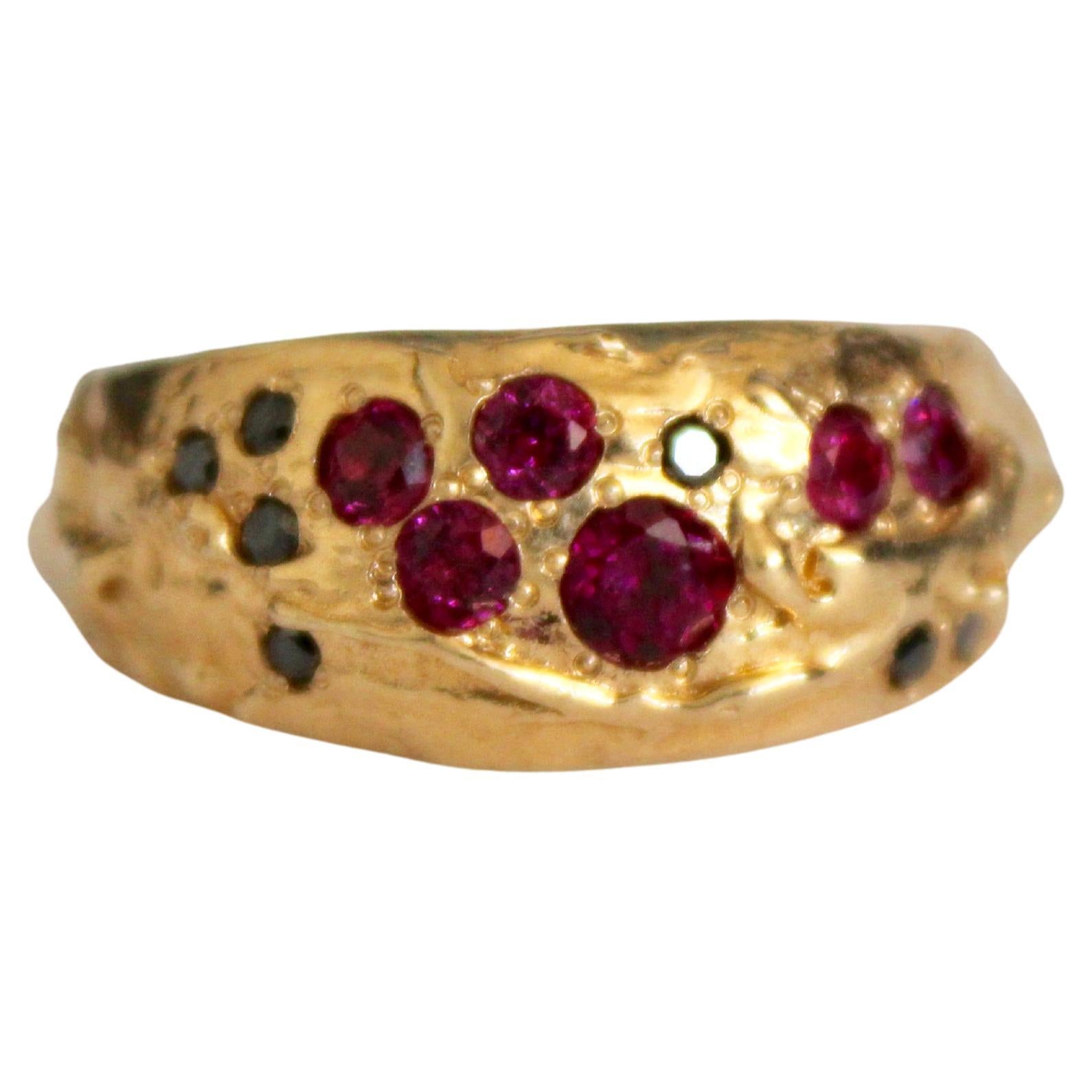 This unisex style is solid 14k yellow gold with pave set black diamonds and garnets. A unique and one of a kind ring, this piece tappers slightly to the back and raises slightly at the front the create a dome like shape. Textured throughout, with