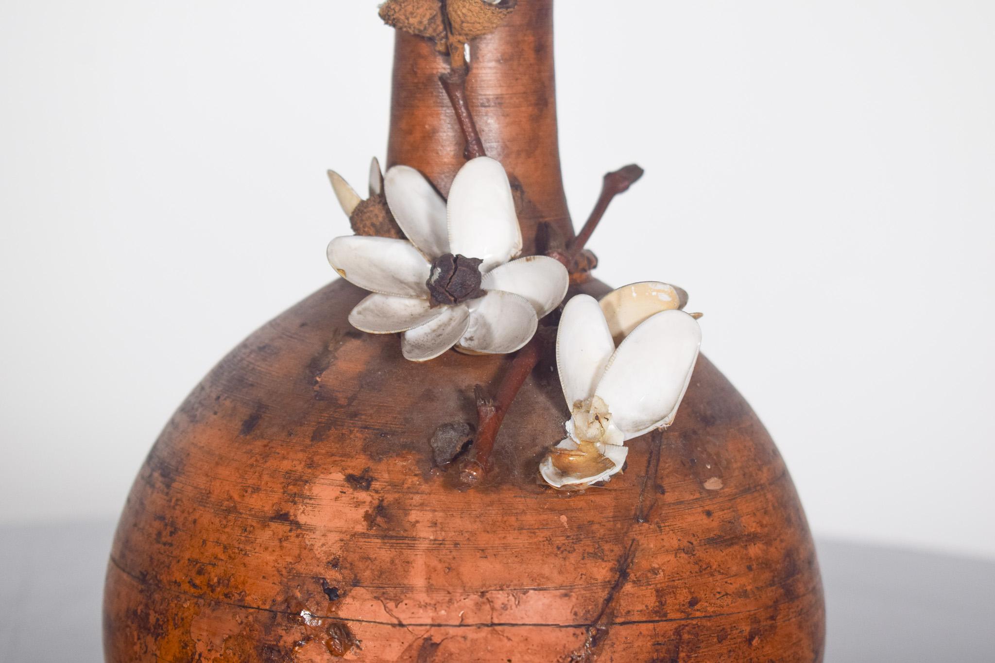 Gewölbte Flasche, aus bräunlicher Keramik. Die geschwungene Form und der dünne, langgestreckte Hals sorgen für ein harmonisches Gleichgewicht zwischen Robustheit und Zartheit. Der bräunliche Farbton mit dunkleren Nuancen und einer strukturierten