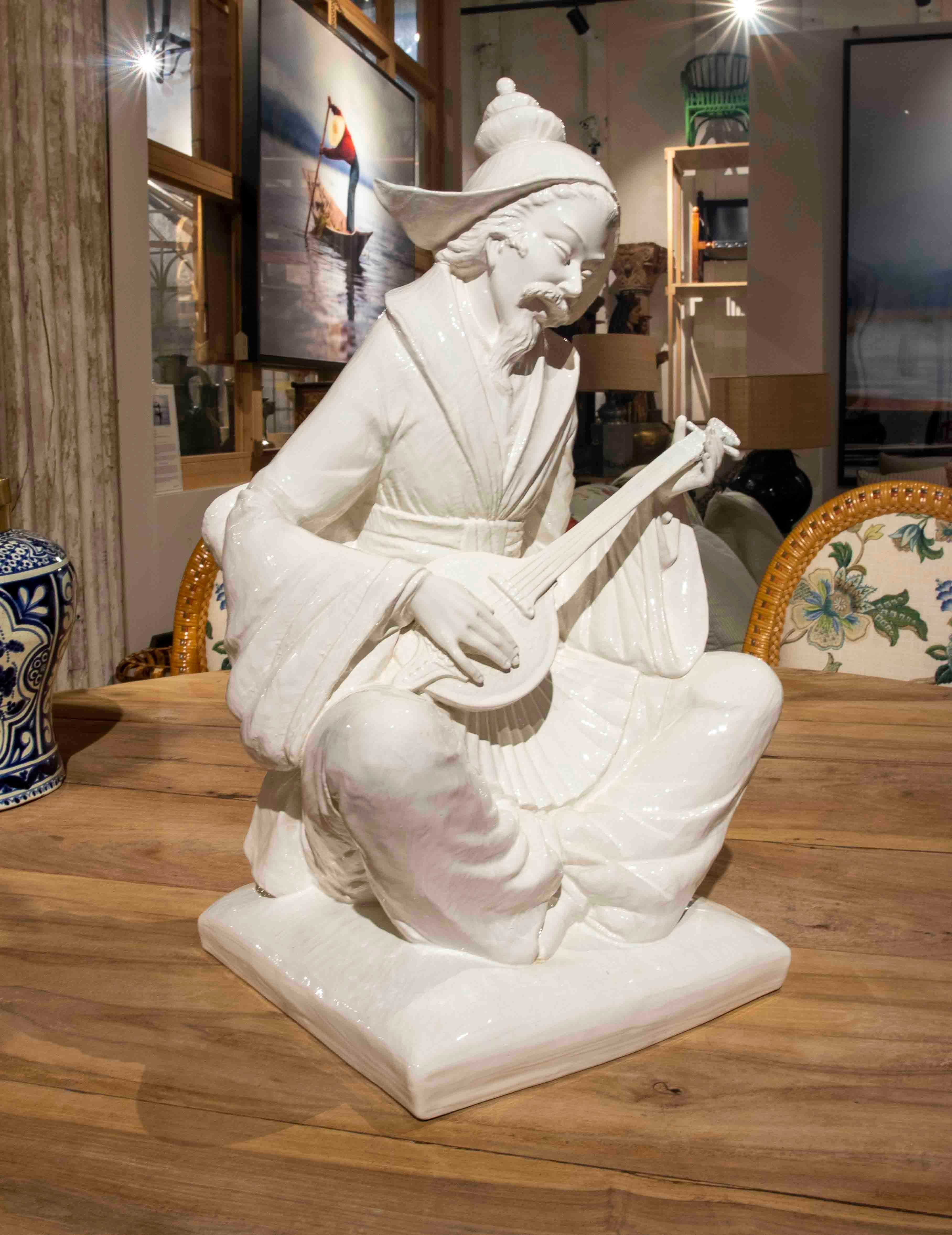 White Glazed Ceramic Figure of an Oriental Character with a Musical Instrument