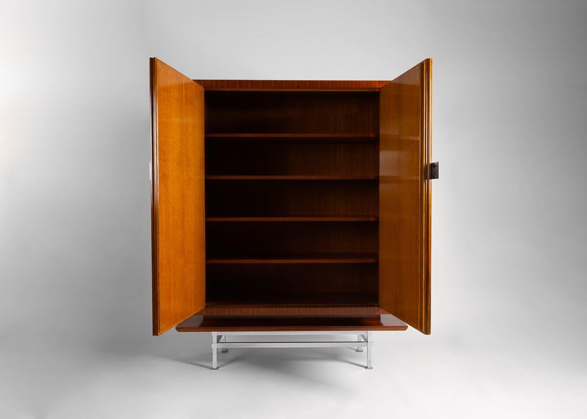 This beautiful midcentury cabinet by André Domin and Marcel Genevrière, made in France in late 1950s, rests on a brushed steel frame.

Dominique quickly rose to prominence via commissions for silver designer Jean Puiforcat and perfumer Houbigant.