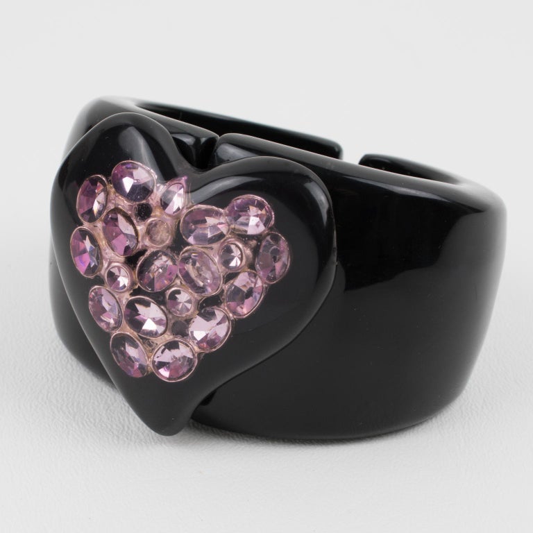 A gorgeous French designer Dominique Denaive, Paris oversized clamper bracelet. 
The piece features a licorice black resin clamper shape with a large heart-shaped cabochon. The heart cabochon has lavender-purple crystal rhinestones embedded in the
