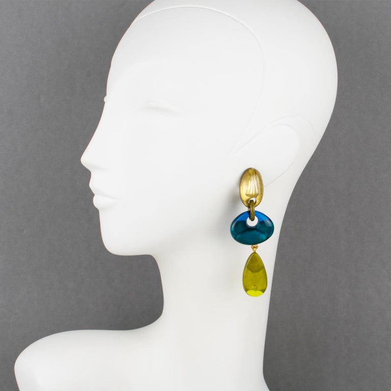 Fabulous clip-on earrings by Dominique Denaive Paris. Dangling shape in resin with drops and free-form donuts in a lovely blue and green olive oil color with pearlized gold inclusions. Gilded metal chains hardware. The engraved signature at the back