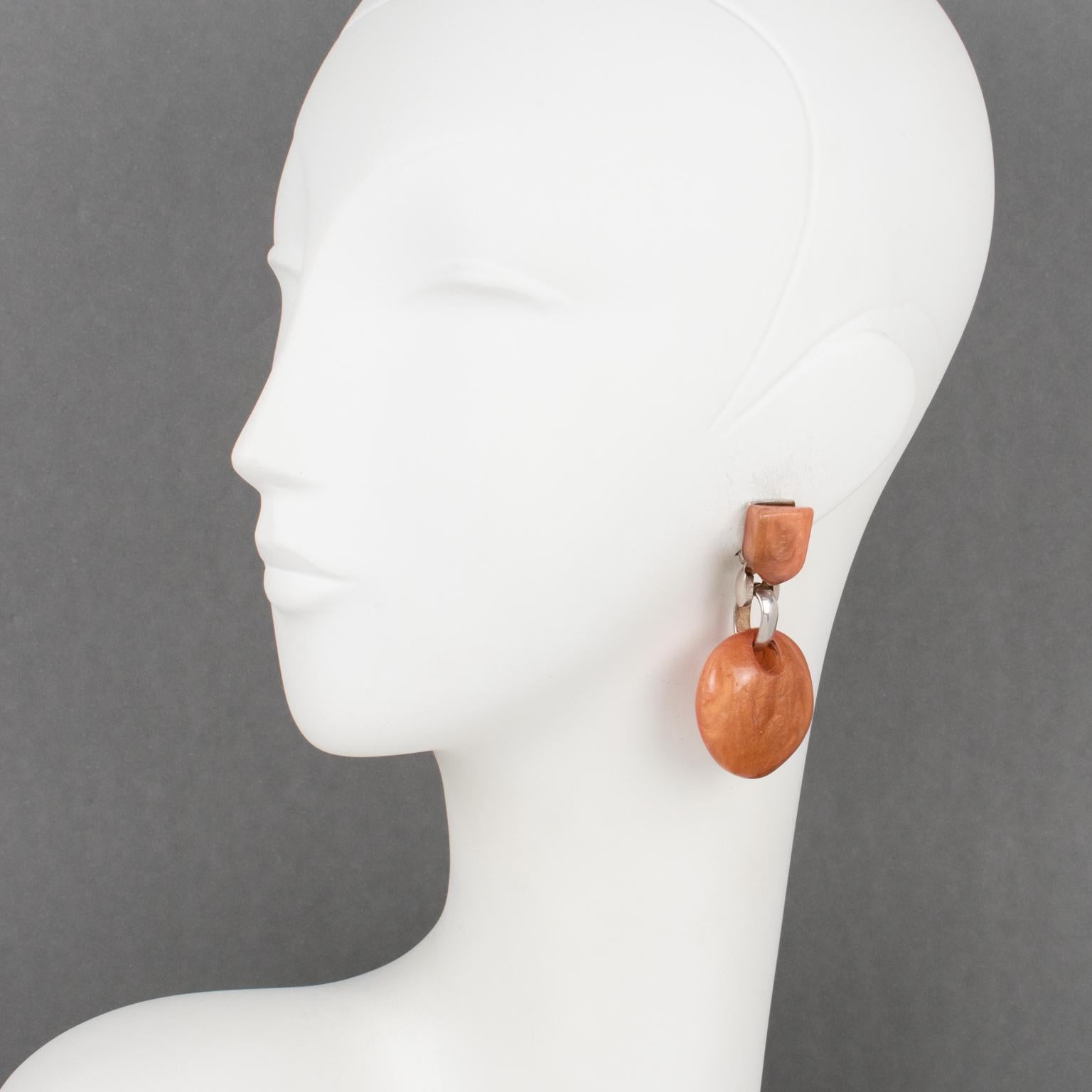 Dominique Denaive Paris crafted these elegant dangle clip-on earrings in his craft shop in France. The pieces boast a dangling-drop shape in pearlized resin with rounded pebbles in a lovely orange cantaloupe color. The hardware is in silvered metal.