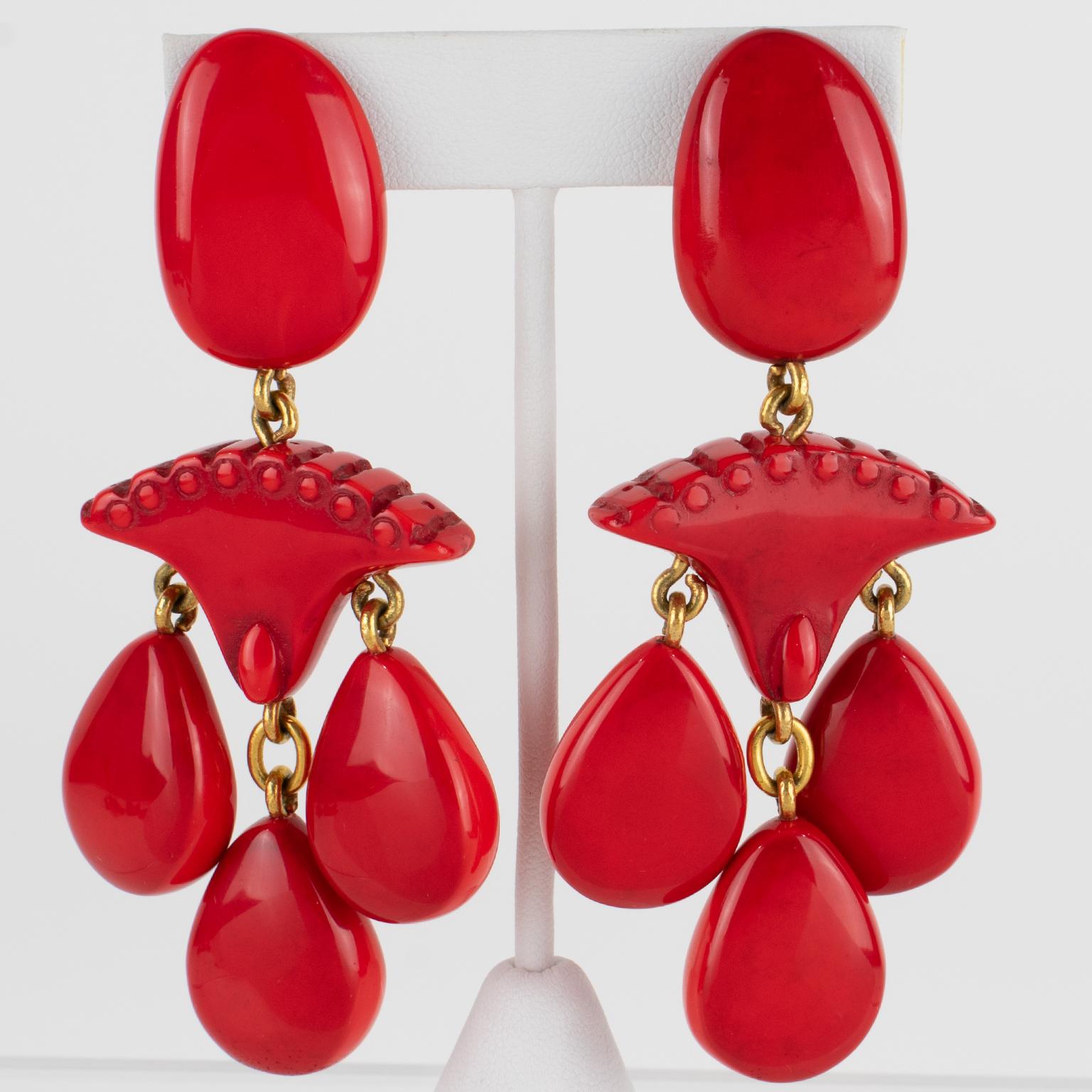 Dominique Denaive Paris ha disegnato questi splendidi orecchini a clip in resina oversize. La forma scultorea del lampadario penzolante presenta elementi intagliati e gocce a goccia in un bellissimo colore rosso con una sfumatura nera. Un orecchino
