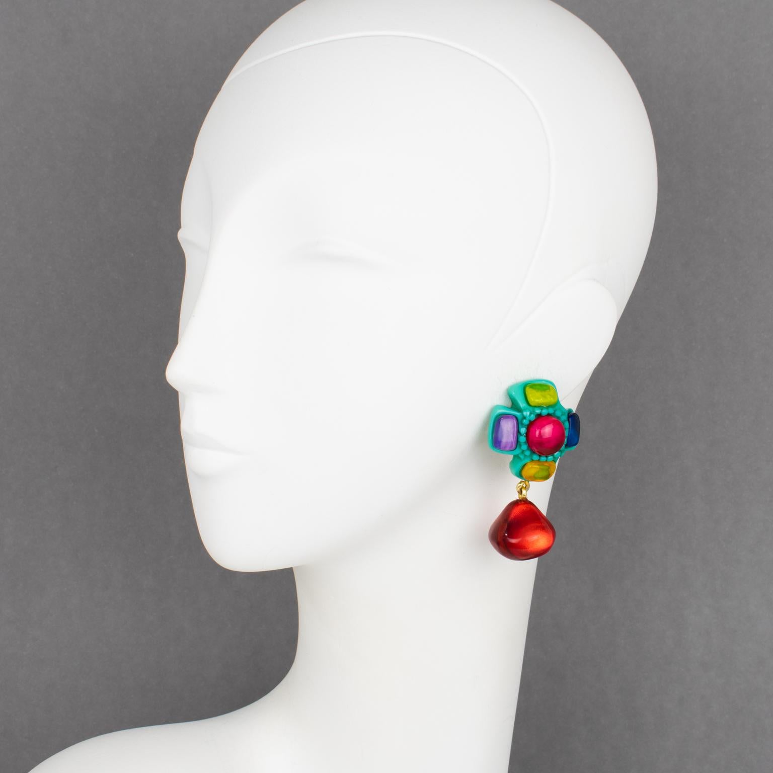 Dominique Denaive Paris designed these gorgeous dangling clip-on earrings. They feature a carved cross shape embellished with multicolor cabochons and dangling drop bead charms. The solid turquoise green color cross framing is contrasted with