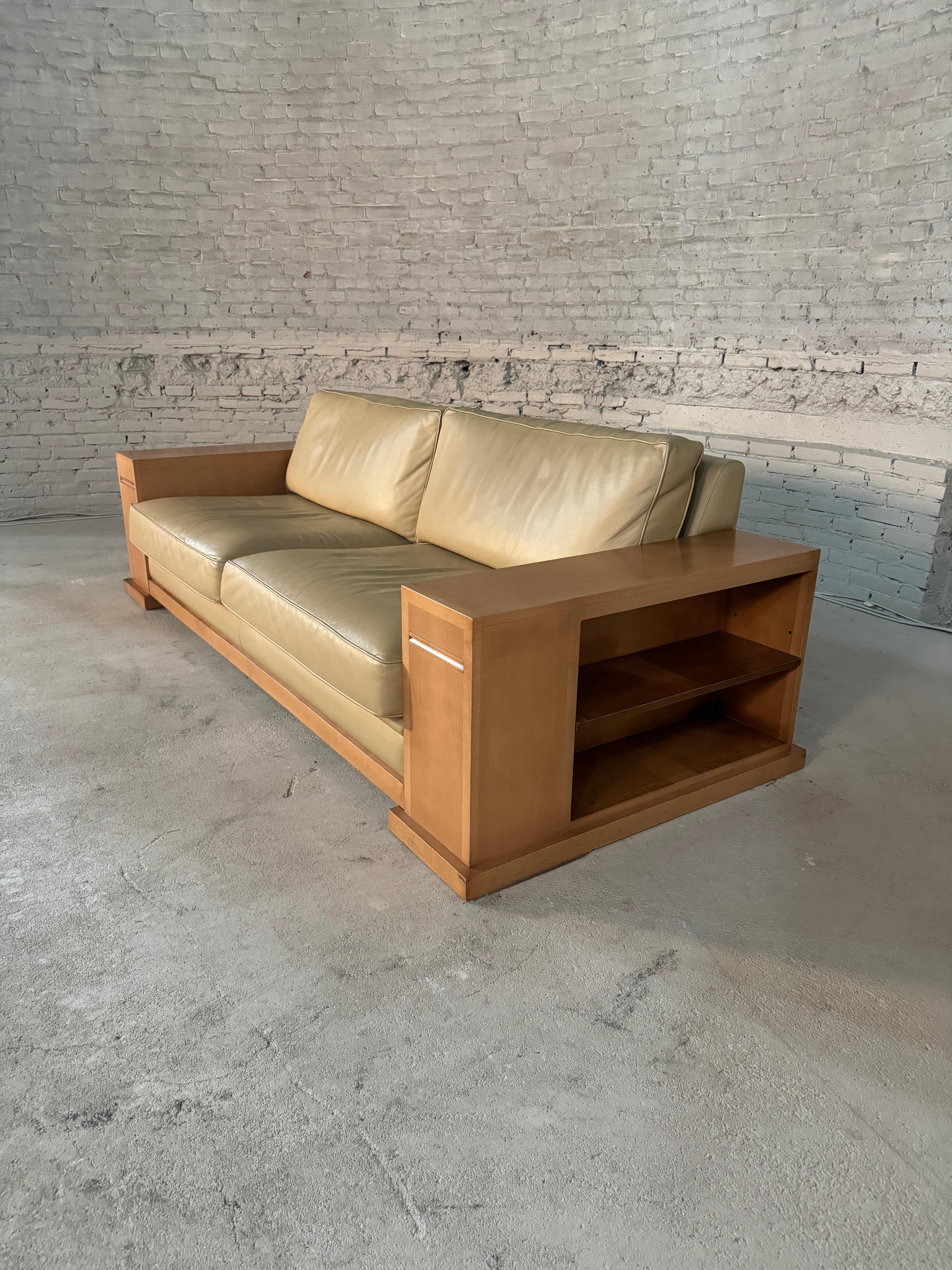 Ce canapé Dominique de Hugues Chevalier présente un design unique et luxueux avec des bibliothèques sur les côtés et des supports en verre extensibles. Il est revêtu d'un cuir doux comme du beurre et les pieds sont en magnifique sycomore. La