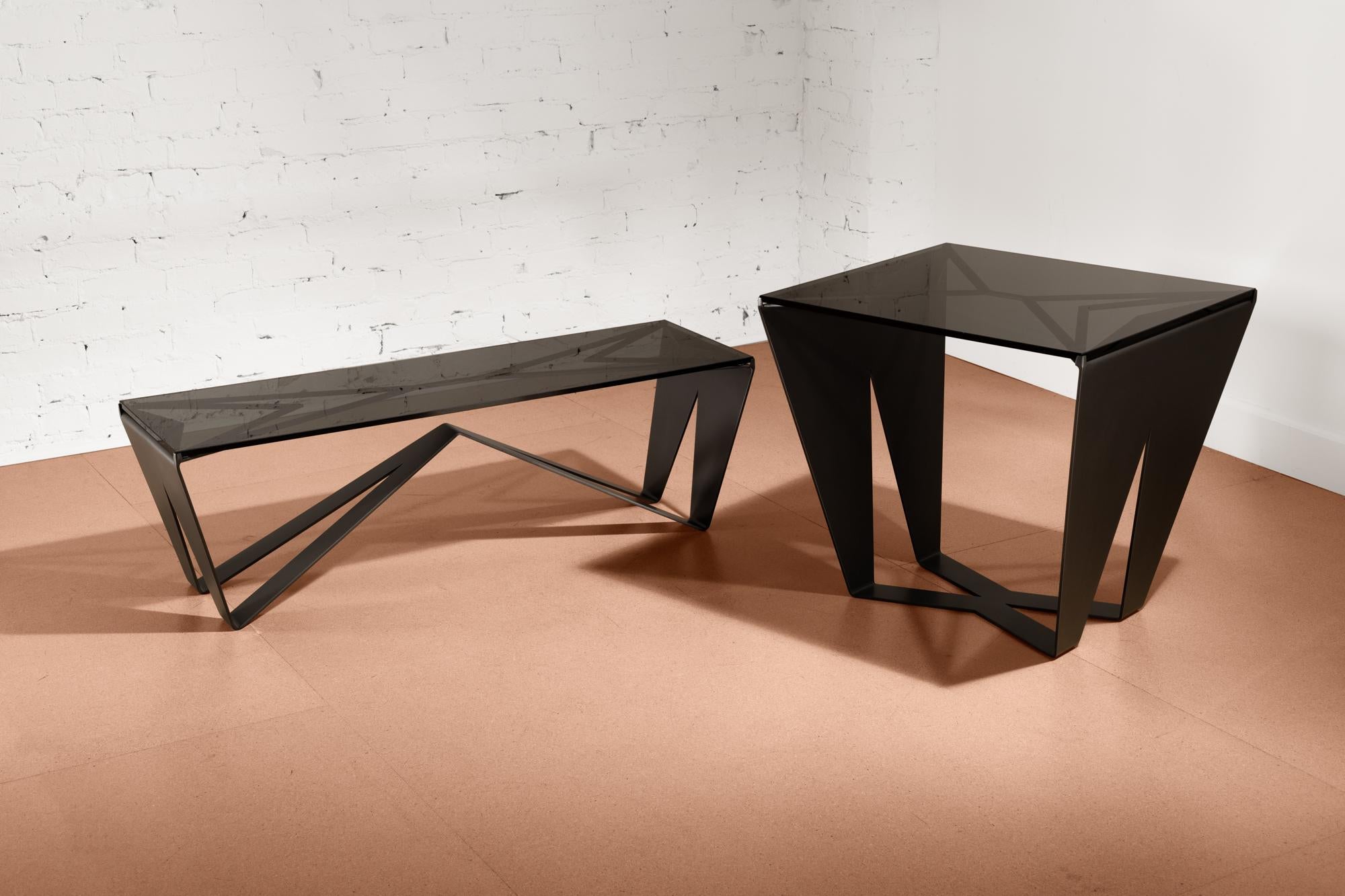 The Domino Coffee Table is part of a nesting duo of tables finely constructed and finished with satin black oxide steel and smoked glass. This table is as functional as it is an art furniture piece for the home with its intricate geometry. The