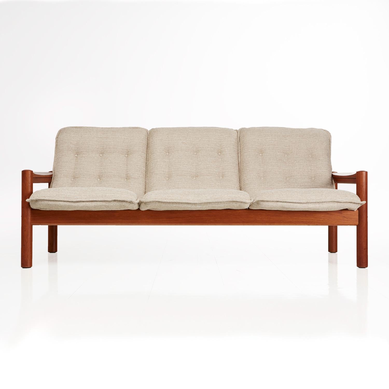 Domino Mobler three-seat couch restored to near mint condition. Solid teak frame with rigid construction. The sculpted arms stand out within the sleek, Minimalist, modern, low profile design. Button tufted in the original pattern. This piece is a