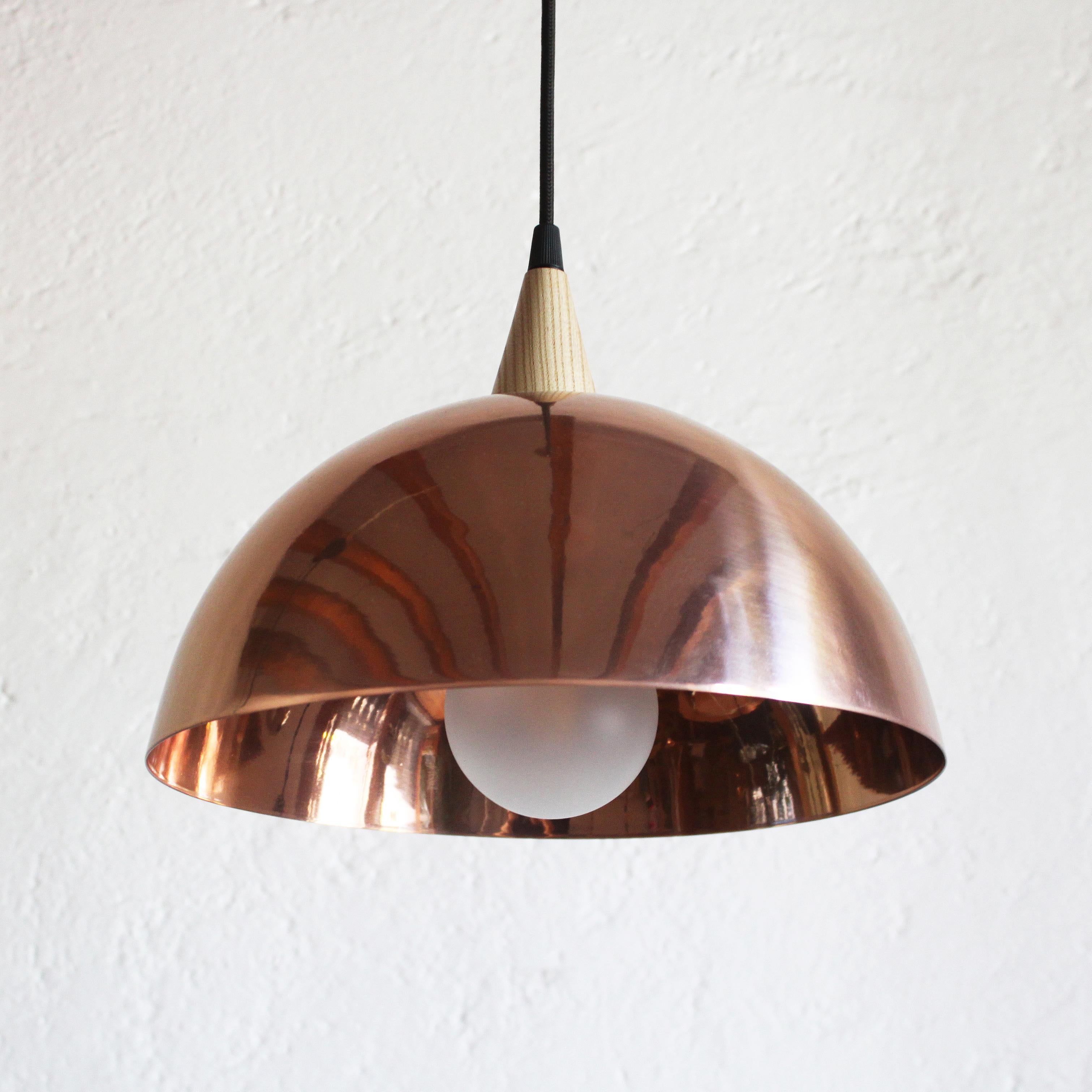 Domo Abajo is a ceiling lamp with dimmable feature (dimmer wall control not included). This pendant features a steel structure covered in electrostatic metal finish and wood detail. The dome is connected to the ceiling with adjustable black fabric