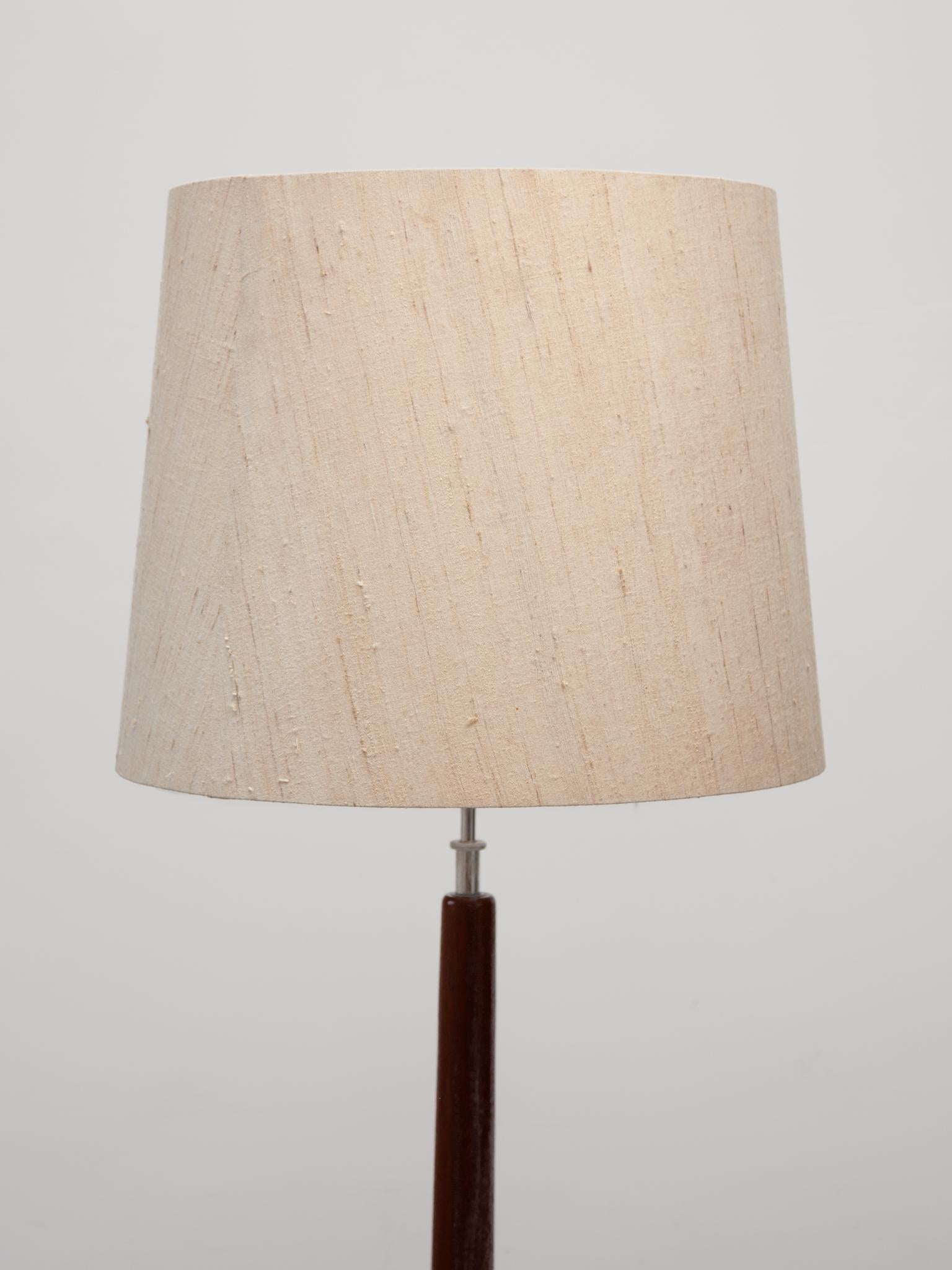 Midcentury Modern minimalist floor lamp manufactured by Domus during the 1960s. It features a stem and base made from solid teak wood, with a beautiful wood grain in a very warm tone.Three light sources can be switched separately: There are two