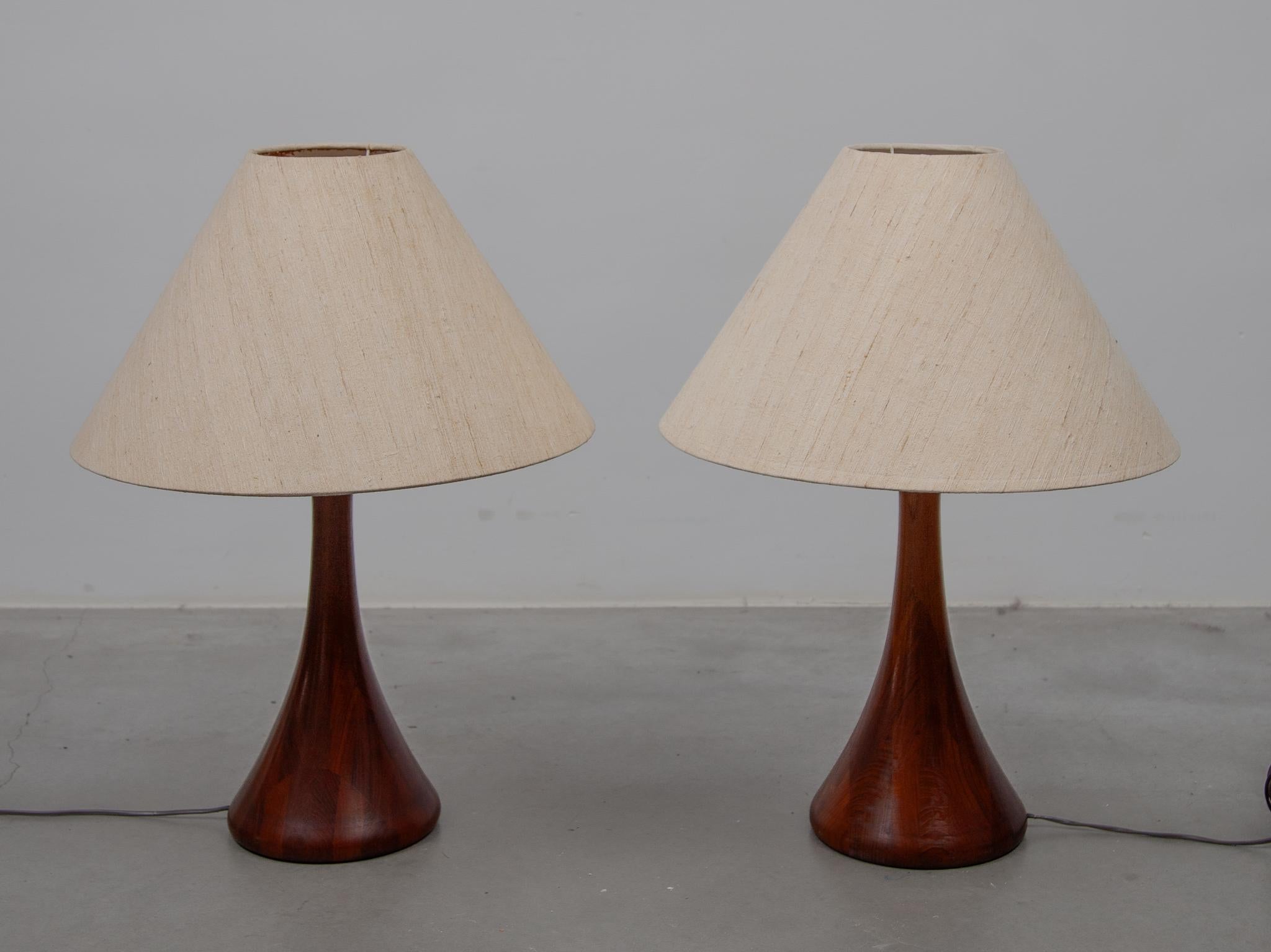 Impressive set of two table lamps in solid teak designed by Domus, made in Denmark with original linen shades The set table lamps are beautiful patinated and are really nice on a mid-century sideboard. Labeled and numbered.