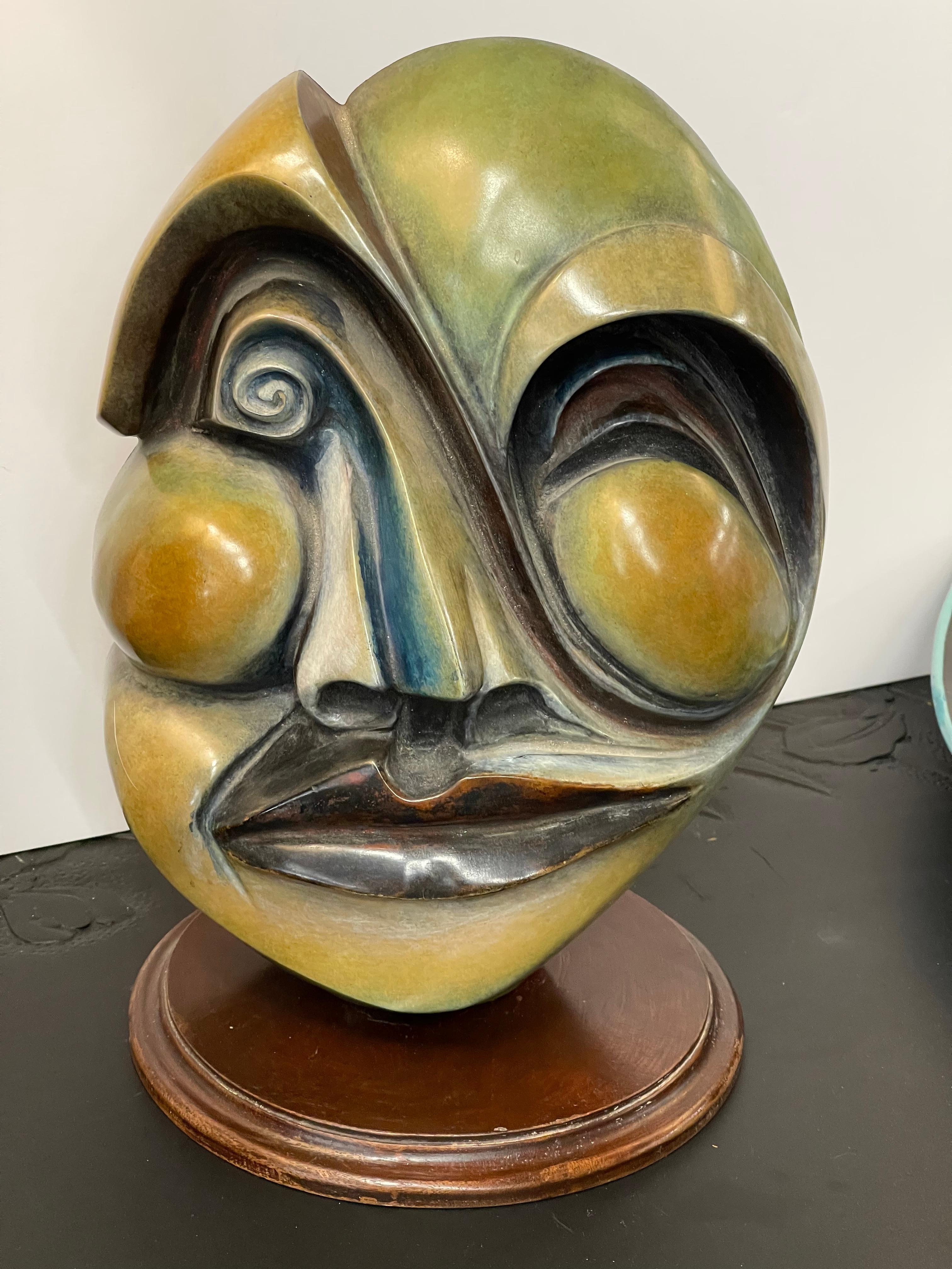 A whimsical bronze mask by the noted California artist Don Riggs. It is signed and dated 1994. Numbered 14/50 although we’re not sure how many oof this edition were actually produced. It is wired to hang, but it is accompanied by a wood base. The