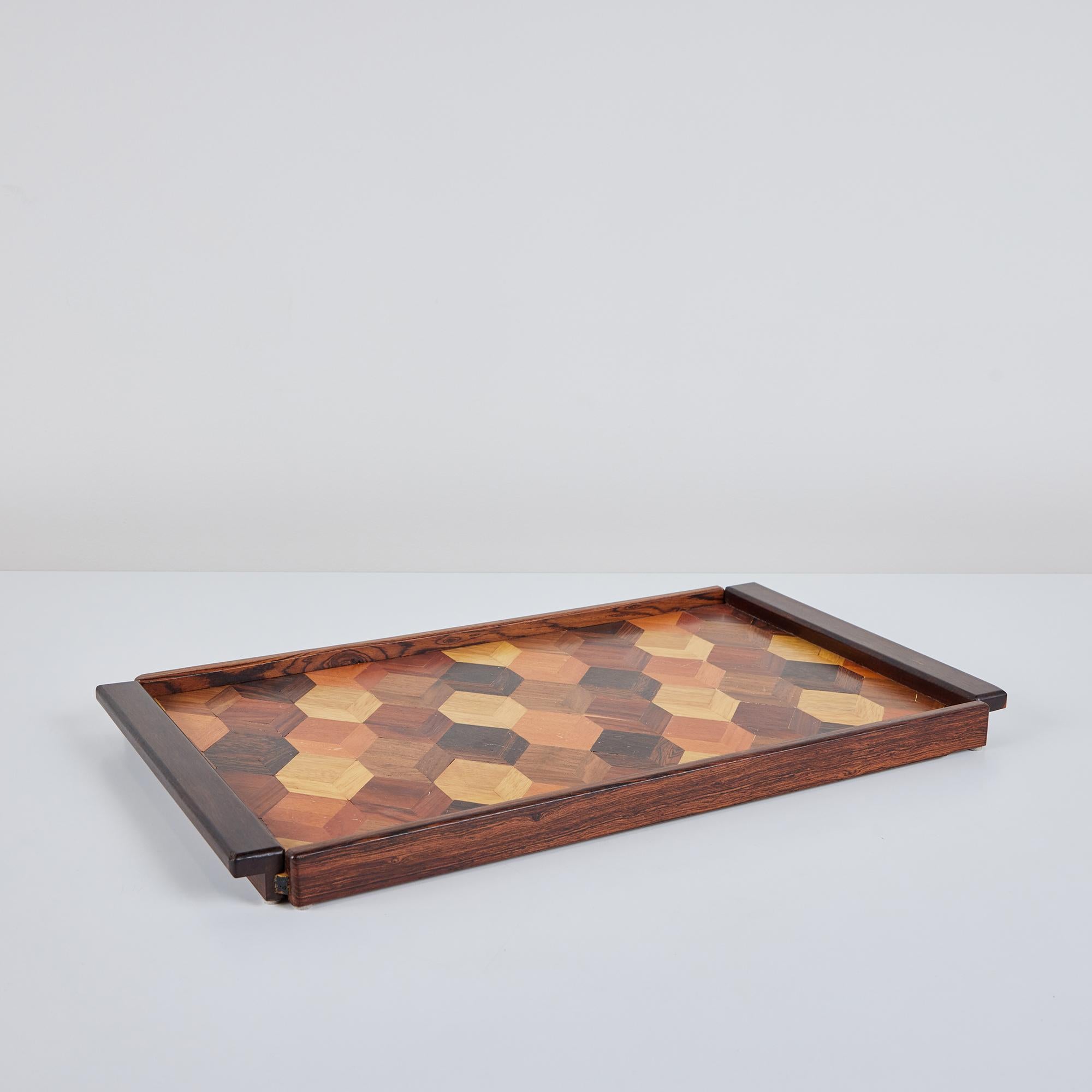 A rosewood serving tray by Don Shoemaker for his company Señal in the 1960s. The surface of the tray has a repeating geometric marquetry pattern in a gradient of local Mexican hardwoods. The rectangular tray has four sides and two handles.

CITES