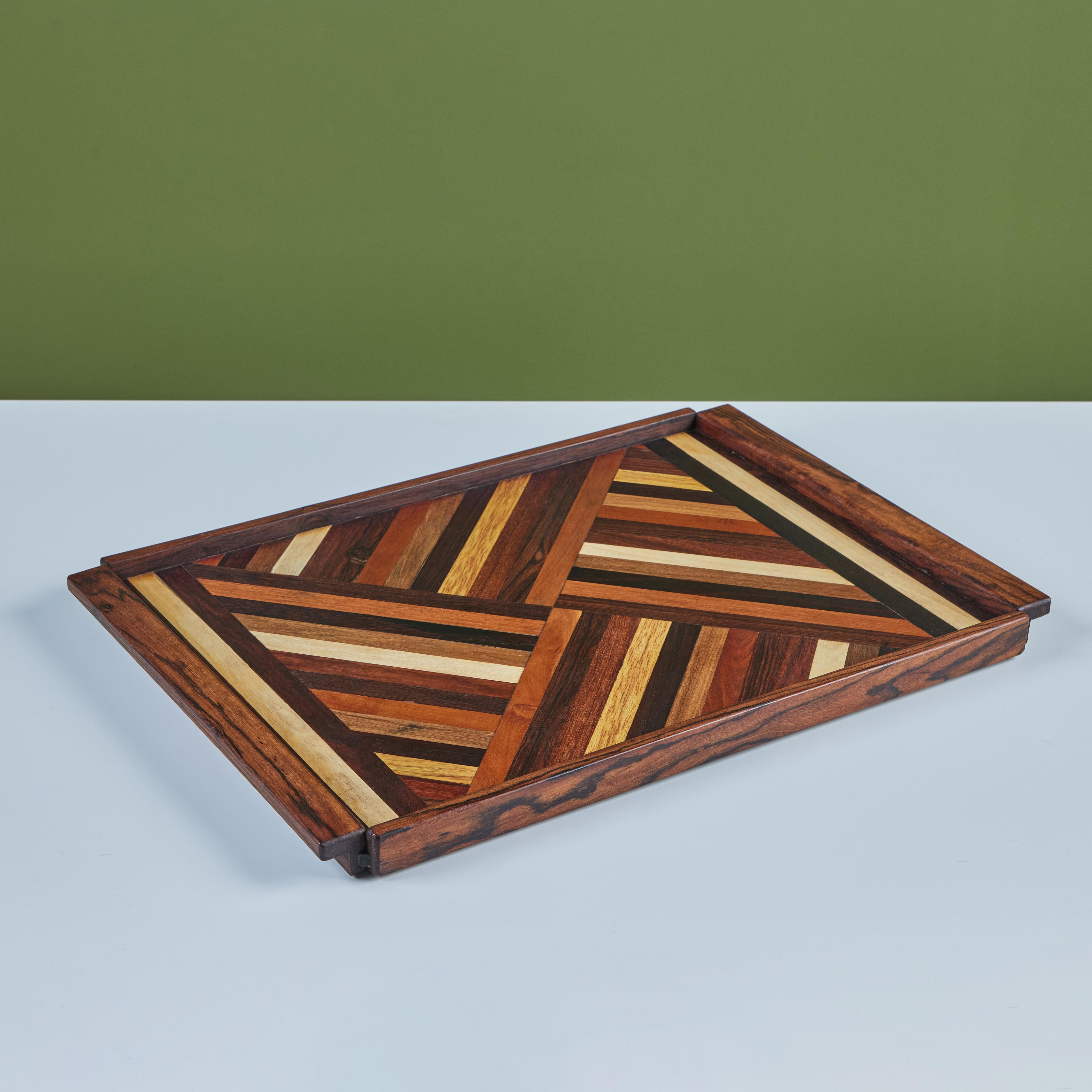 A rosewood serving tray by Don Shoemaker for his company Señal in the 1960s. The surface of the tray has a repeating geometric marquetry pattern in a gradient of local Mexican hardwoods. The rectangular tray has four sides and two handles.

A