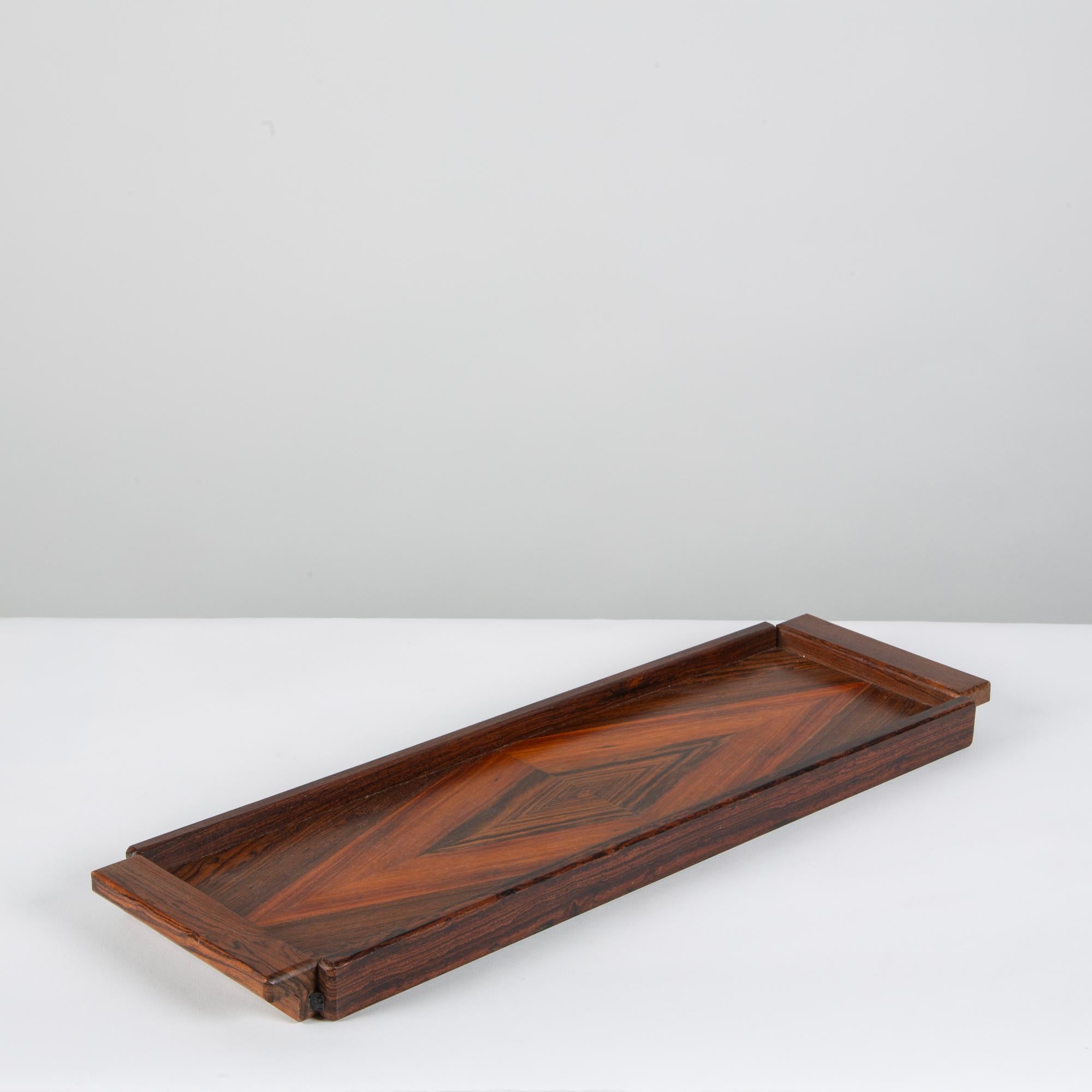 A narrow serving tray by Don Shoemaker for Senal of Mexico. The tray has a dark rosewood frame with integrated handles at either end, and the tray surface is inlaid with precious wood veneer in a diamond pattern. 

CITES Notice: Due to stringent