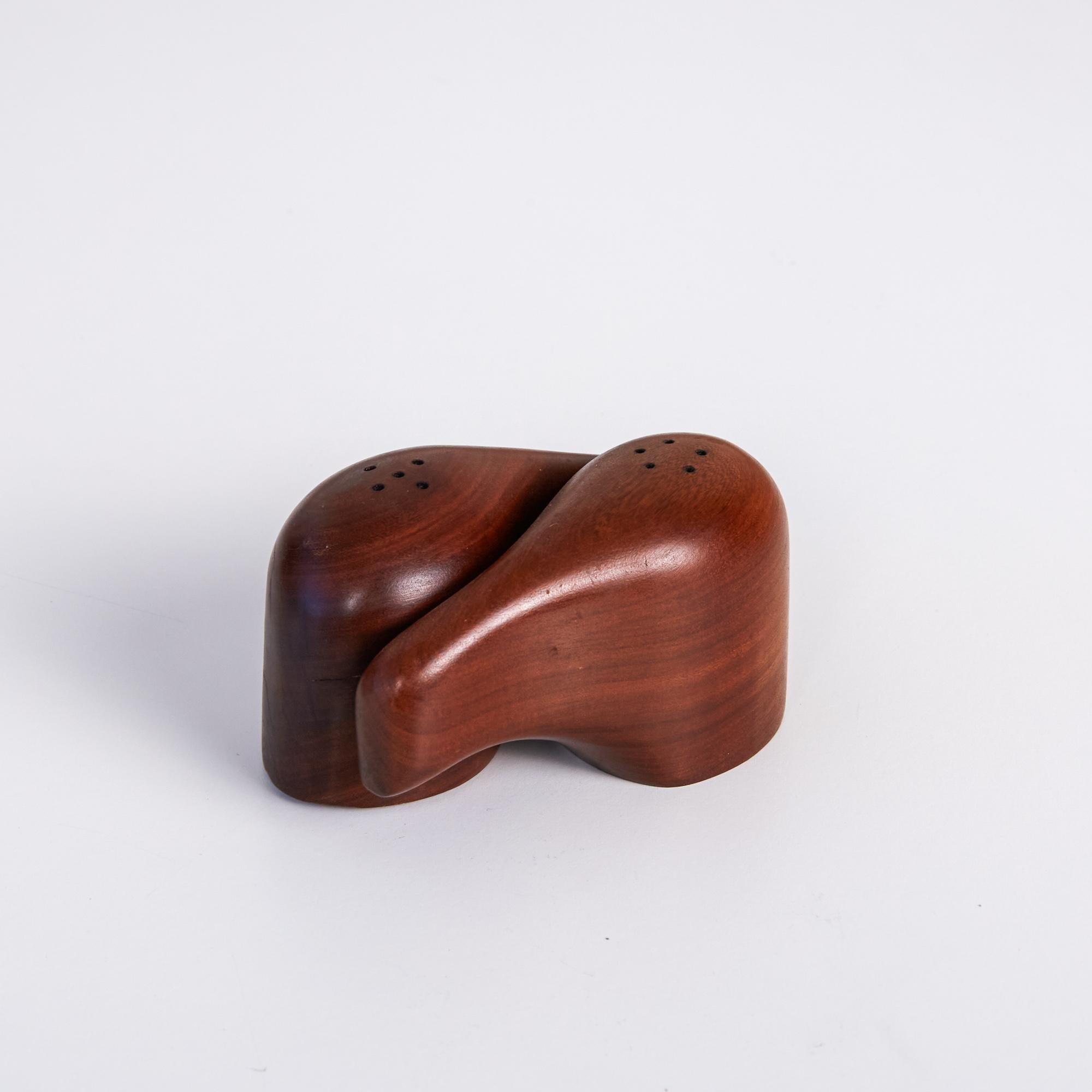 Set of Don Shoemaker for Sen~al salt and pepper shakers. The hand carved Minimalist mahogany shakers feature an interlocking design that, from a glance, makes the two pieces form together as a single object. Each piece features five expertly drilled