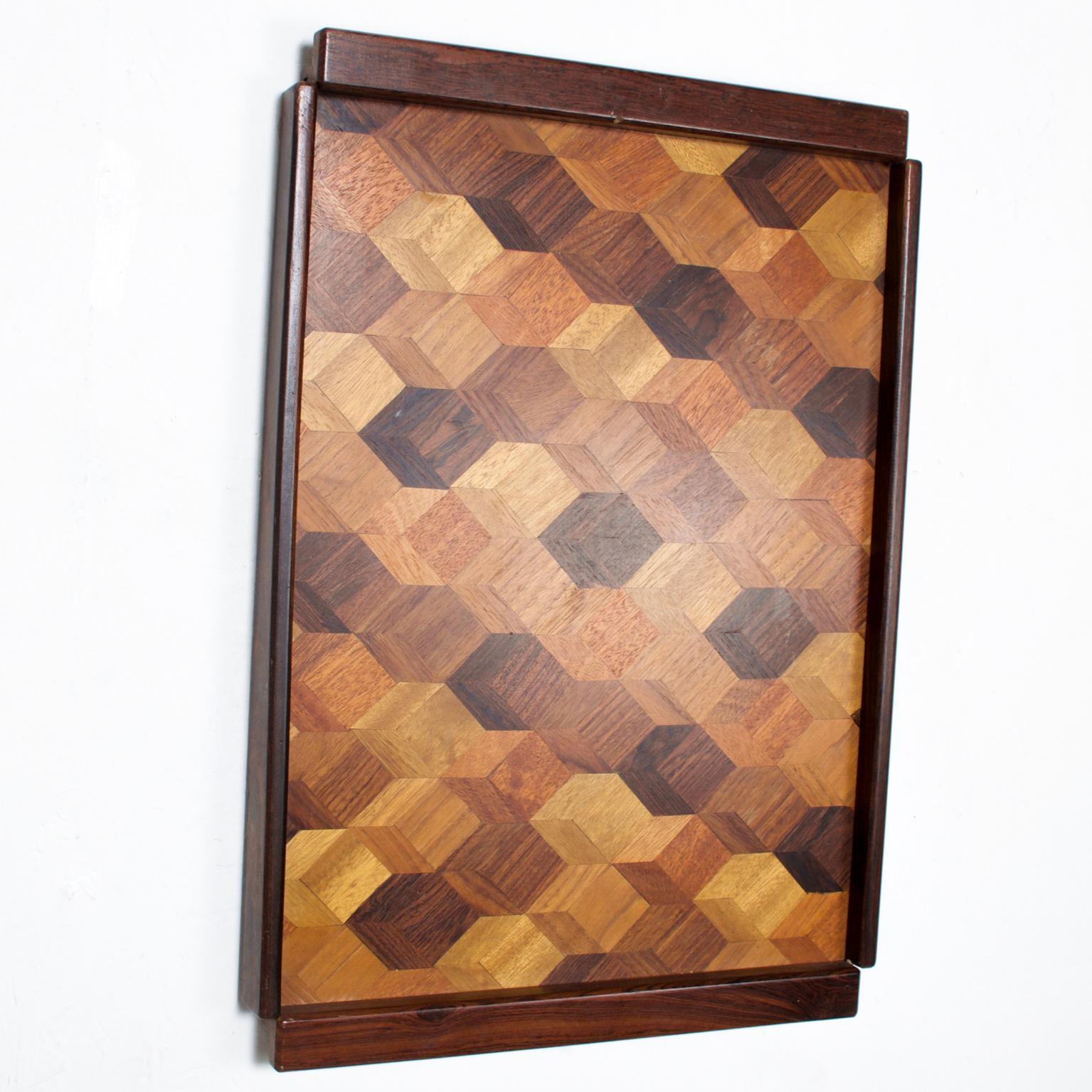 We are pleased to offer for your consideration a Large service tray by Don S Shoemaker. Beautiful geometric woodwork with exotic woods. A small hole on the back of the tray allows easy hanging into the wall. Retains label from the maker on the back.