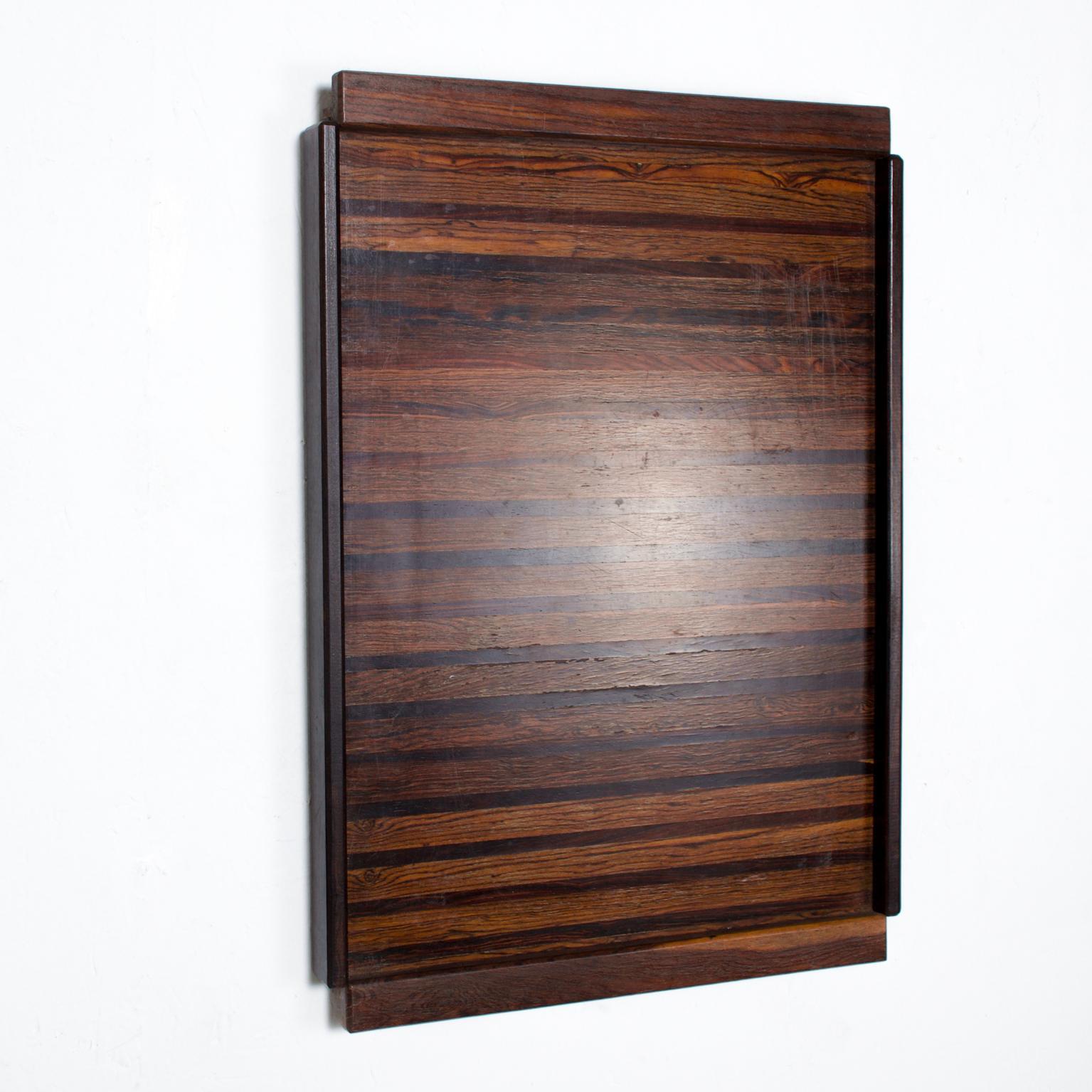 We are pleased to offer for your consideration a Large service tray by Don S Shoemaker. Beautiful straight geometric woodwork with exotic woods. A small hole on the back of the tray allows easy hanging onto the wall. Retains label from the maker on