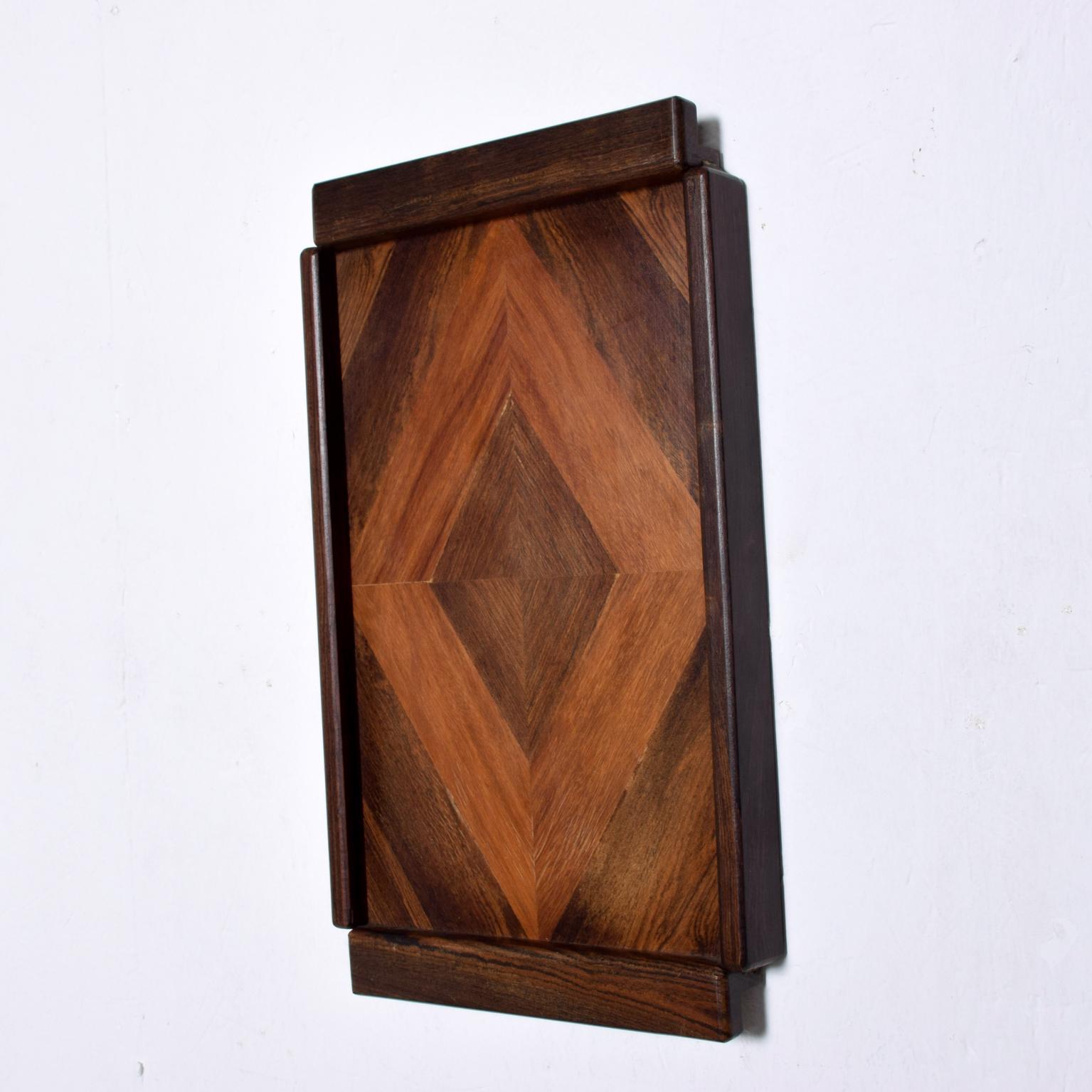 We are pleased to offer for your consideration a Medium service tray by Don S Shoemaker. Beautiful geometric woodwork with exotic woods. A small hole on the back of the tray allows for easy hanging onto the wall. Retains label from the maker on the