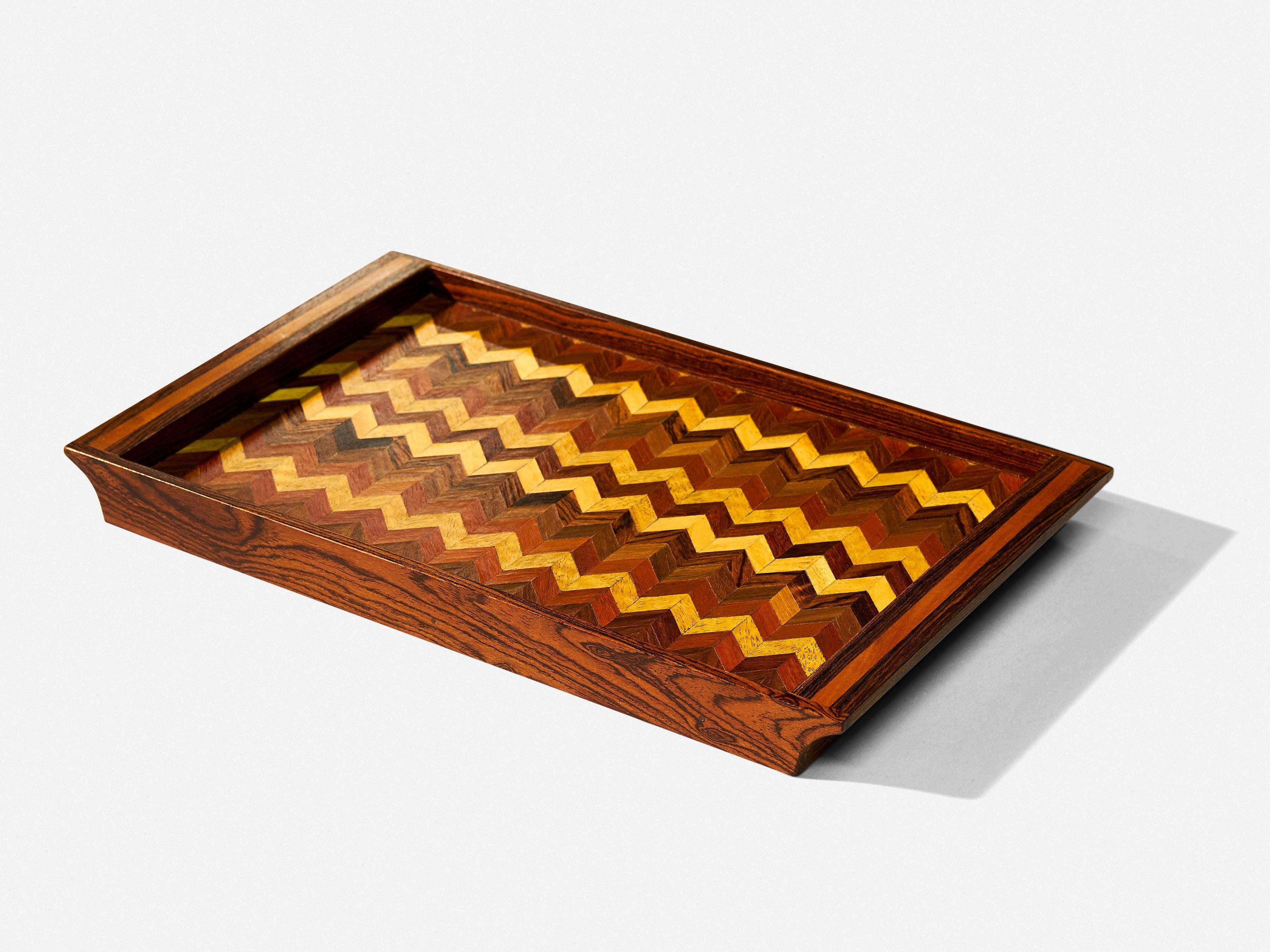 Don shoemaker mixed woods tray by Senàl, circa 1960.

Chevron pattern of mixed exotic wood species trimmed in rosewood.

Excellent vintage condition.

Measures: 22” x 15” x 1.25.