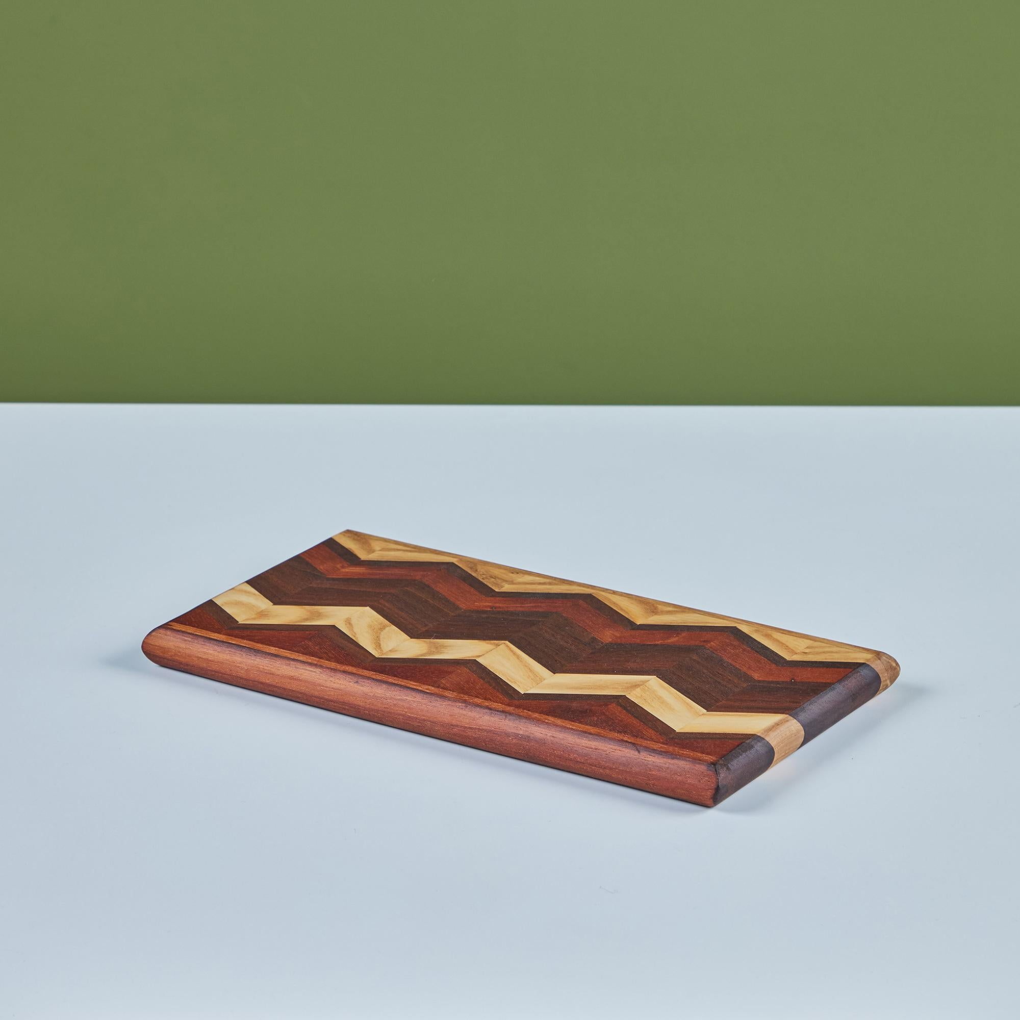 Cutting board by Don Shoemaker for his company Señal in the 1960s. The surface of the board has a repeating chevron marquetry pattern in a gradient of local Mexican hardwoods that can be viewed on both sides. 

CITES Notice: Due to stringent