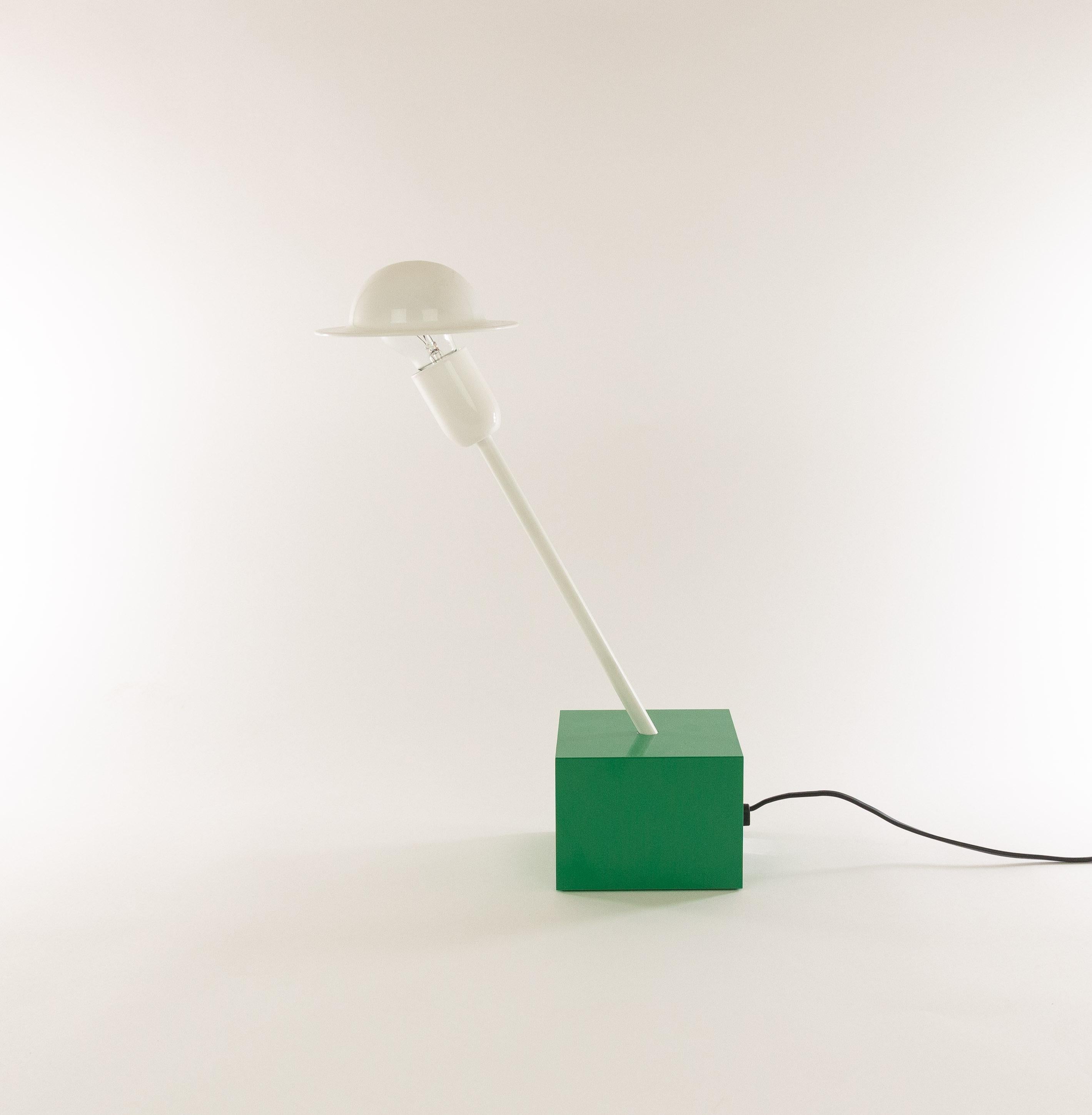 Don table lamp designed in 1977 by Ettore Sottsass and manufactured by Stilnovo.

The lamp consists of a relative heavy emerald green cubic base, a white slanted rod and a striking adjustable white shade. This shade is connected to the light bulb