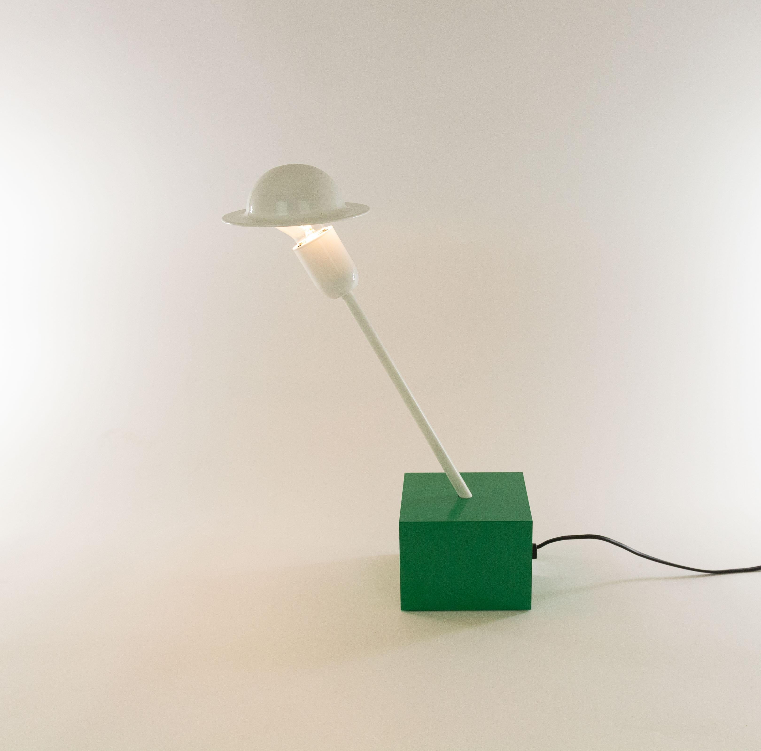 Don table lamp designed in 1977 by Ettore Sottsass and manufactured by Stilnovo.

The lamp consists of a relative heavy emerald green cubic base, a white slanted rod and a striking adjustable white shade. This shade is connected to the light bulb