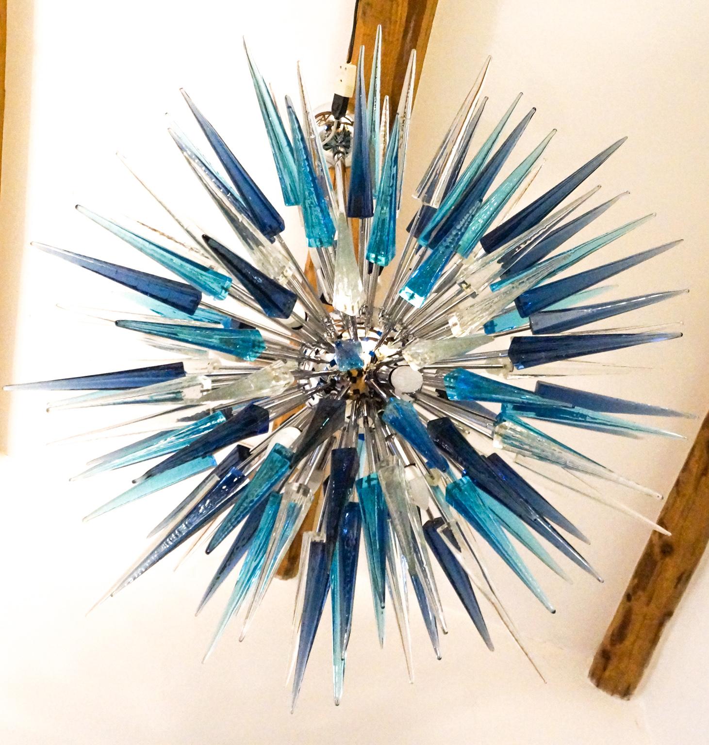 Perfect for a modern location, this Sputnik is composed by 121 crystal, acquamarine and blue grey tips elements in Murano glass.
Designed by Alberto Dona’, it reach the diameter of 115 cm, so it is very well matchable in large and contemporary