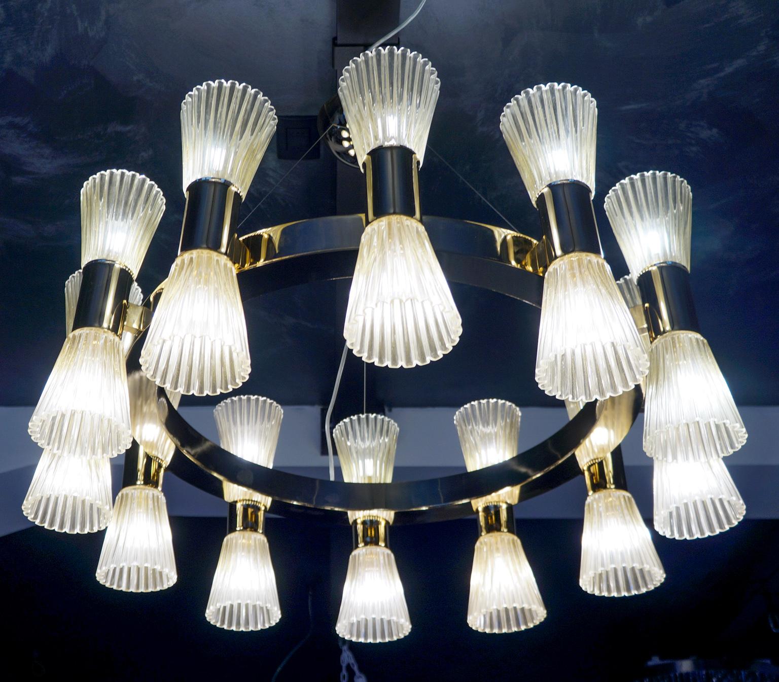 Sostenuto da una cornice rotonda dorata, questo lampadario ha una struttura placcata in oro, decorata con 24 coppe in vetro di Murano decorate con foglia d'oro a 24 carati, in cui è inserita una lampadina a led G9 da 2,5 watt.
Un lampadario