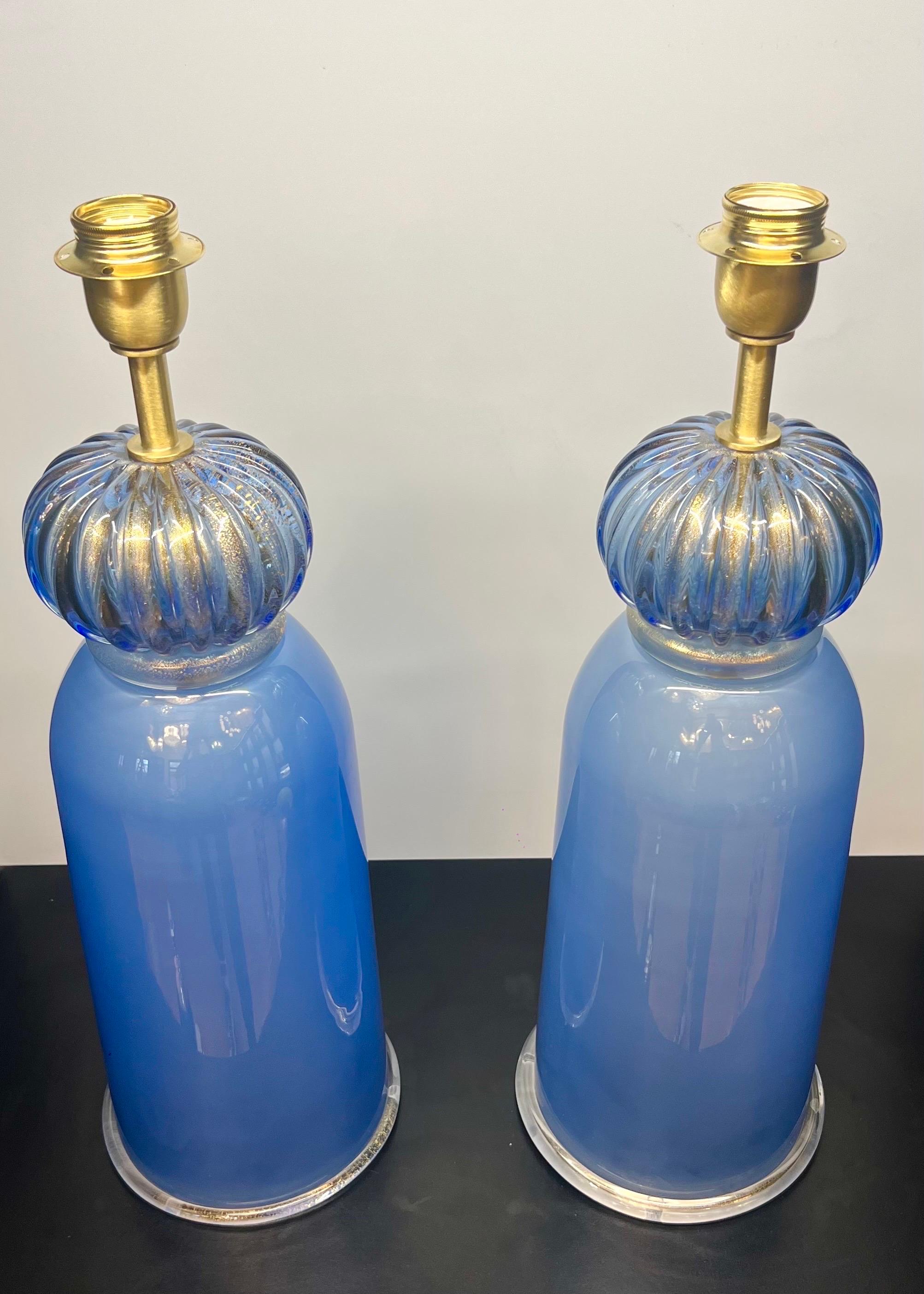 Paire exclusive de lampes de table en verre de Murano bleu clair avec monture en bronze satiné.
La lampe est composée d'un élément en forme d'oignon en or 24 carats et d'un élément en forme de quille.
En touchant de la main l'élément en forme