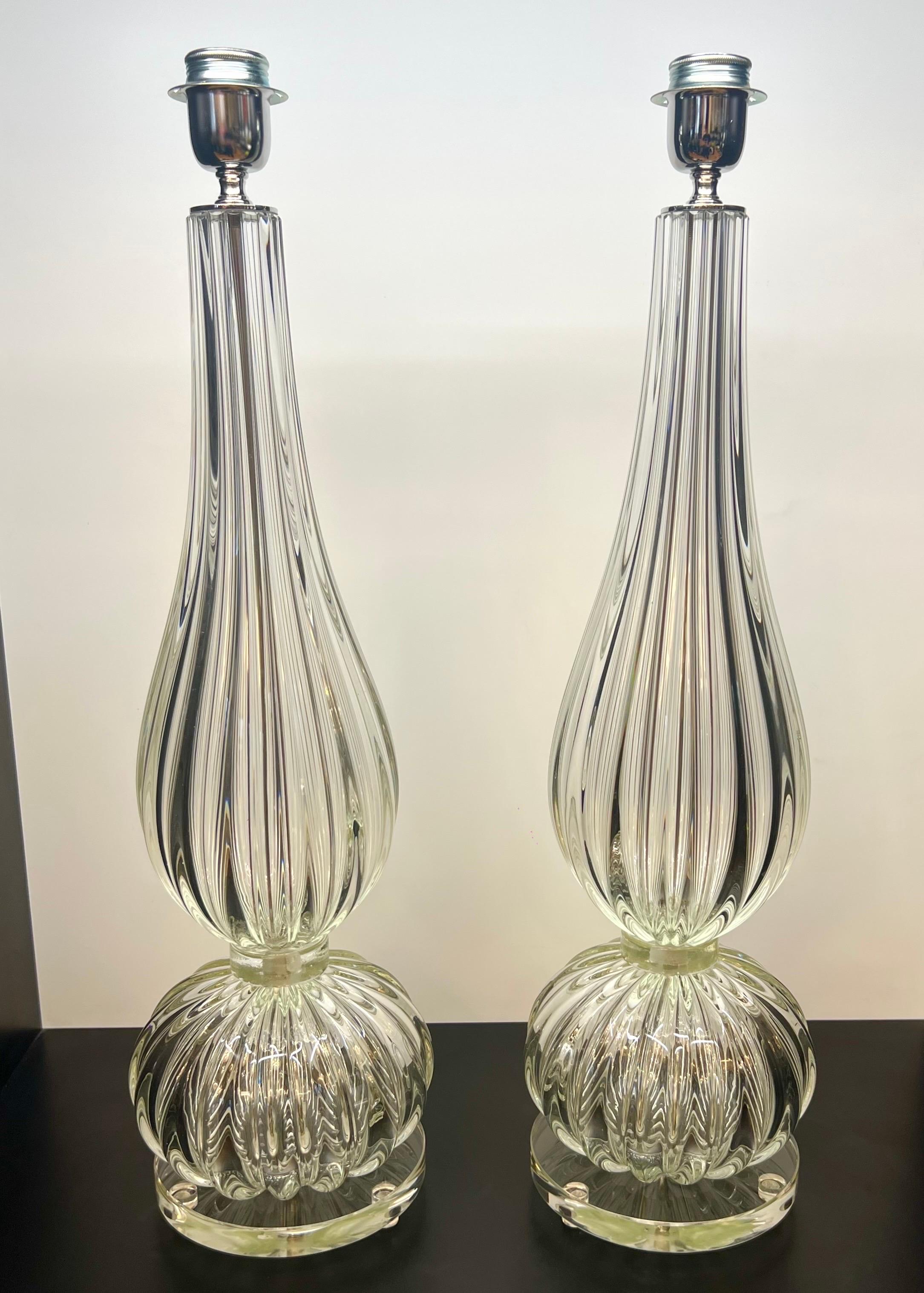Exclusiva pareja de lámparas de sobremesa de cristal de Murano transparente con marco de cromo pulido.
La lámpara está formada por 1 elemento en forma de cebolla y 1 elemento en forma de gota.
Al tocar la lámpara con la mano, notarás la particular