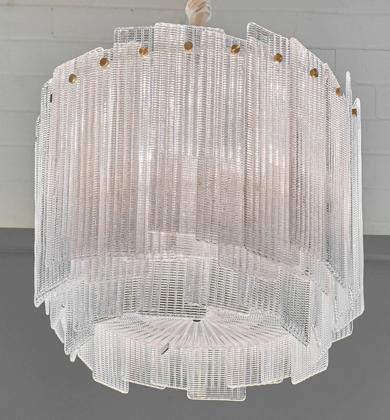 Murano glass “a piastre” chandelier by A Dona– a stunning, bold fixture, featuring a large array of overlapping Murano molded and textured glass blades, held to the structure by brass screws. A molded and textured glass plate finishes the bottom.