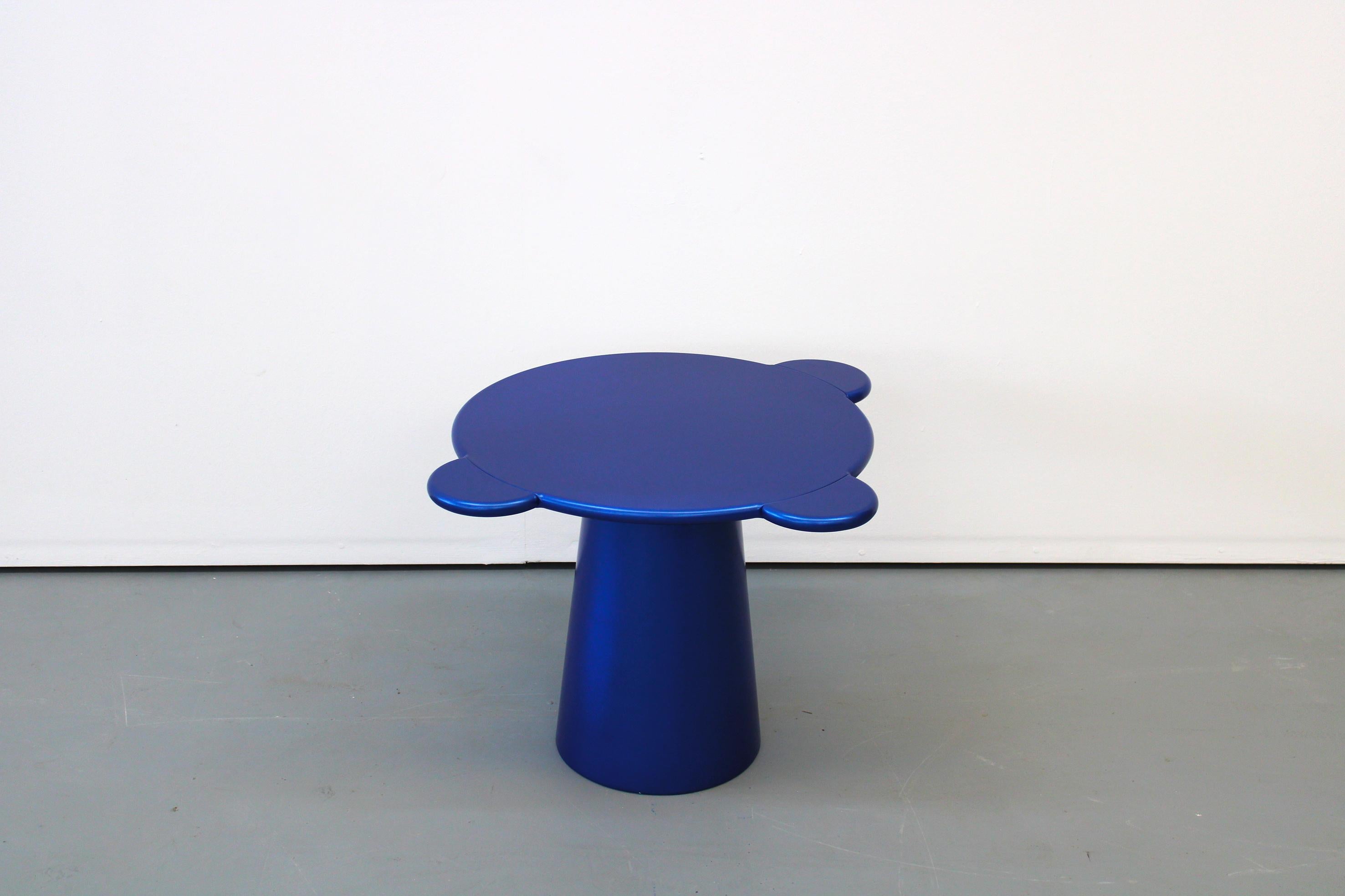 Donald is a multifunctional table with a sculpturally cosmic aspect and colorful circular shapes.
The sculptural silhouette has a wooden structure composed of a truncated cone that supports a round top adorned with three semi-circular flaps, ideal